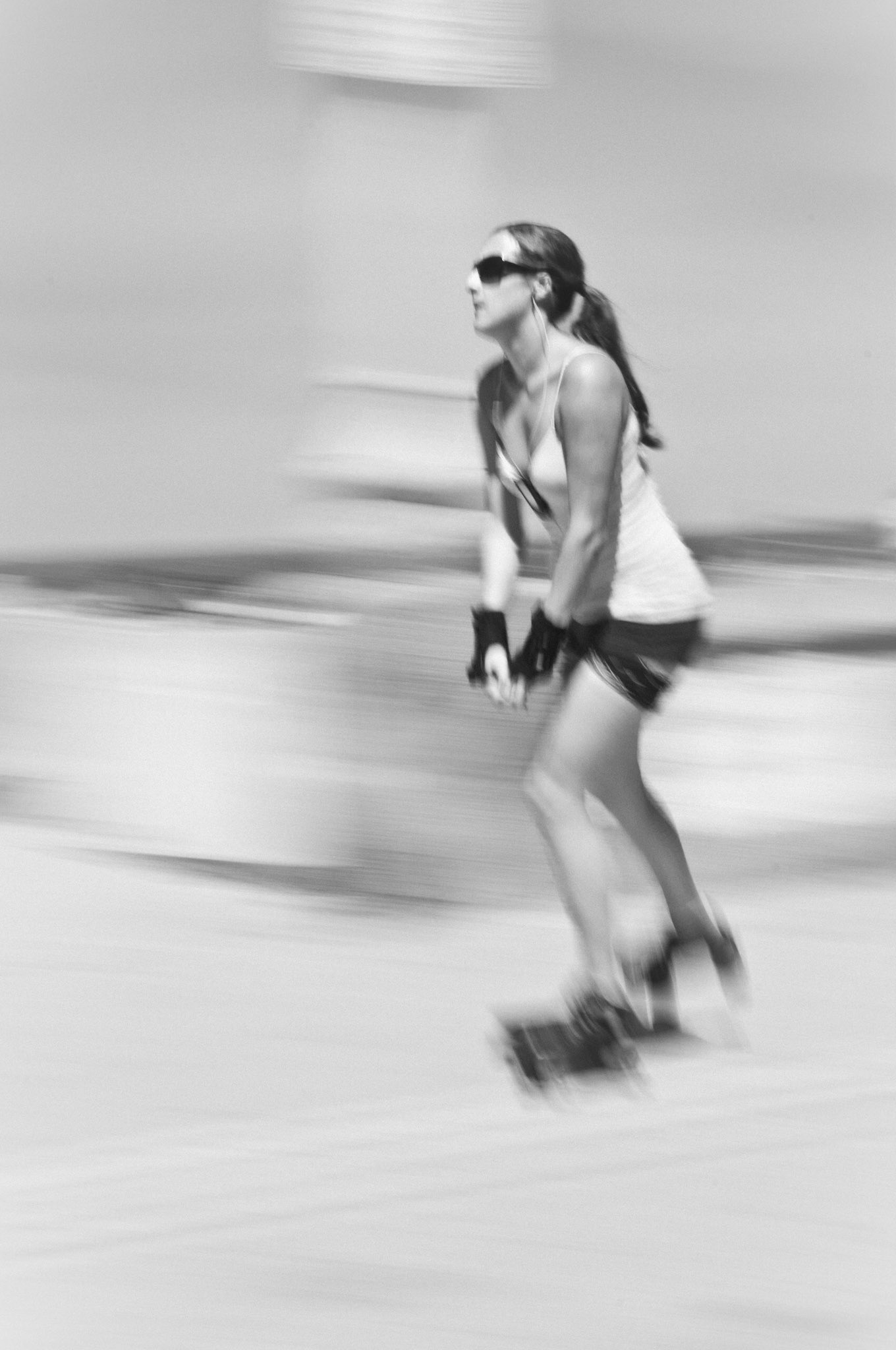 Black and white motion-blur photo of woman roller-blading at Mission Beach, San Diego, California, USA.