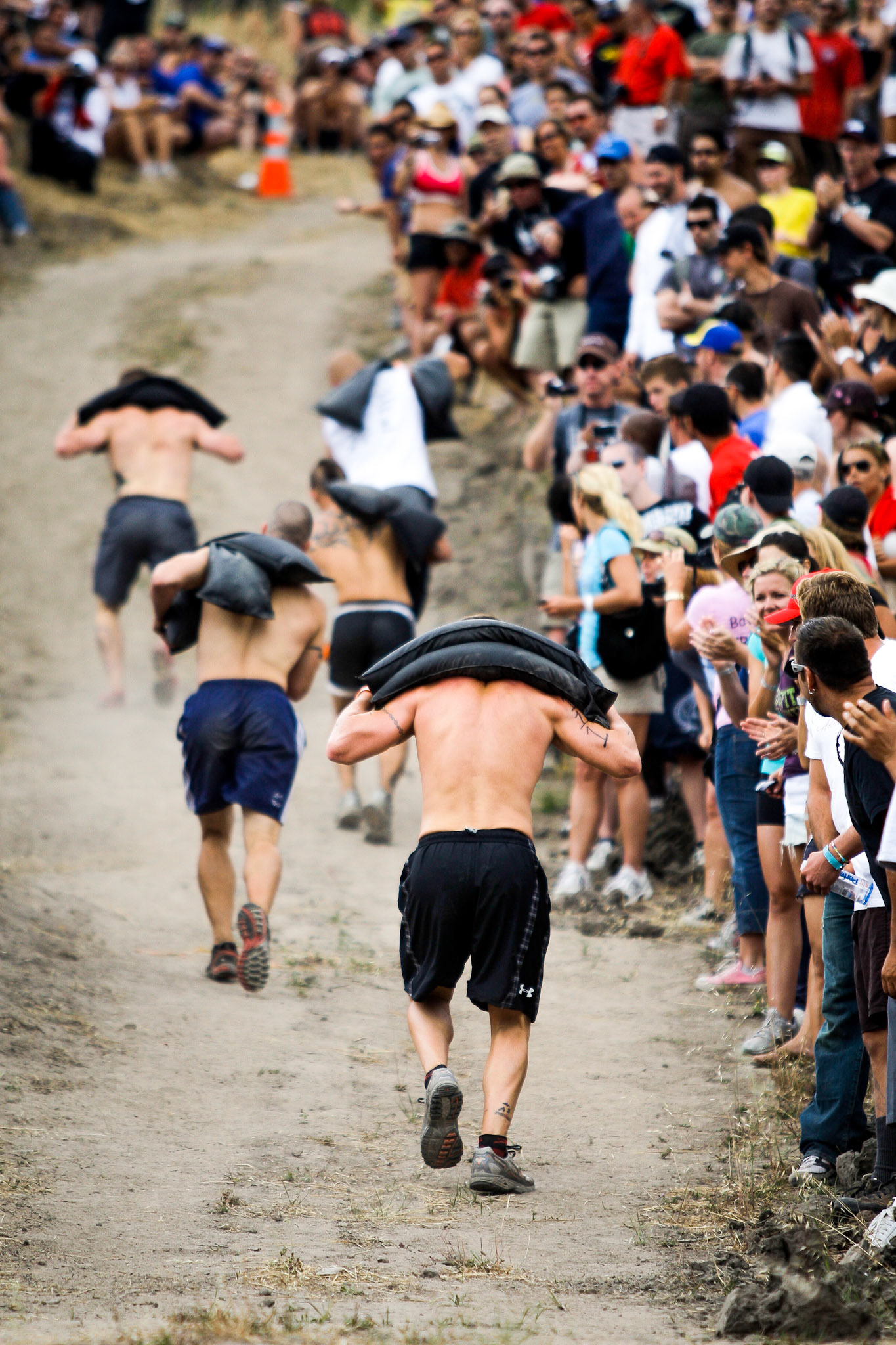 Athletes sprint to the top of a steep hill carrying 70 pounds of sand bags in the 3rd workout of the 2009 CrossFit Games.
