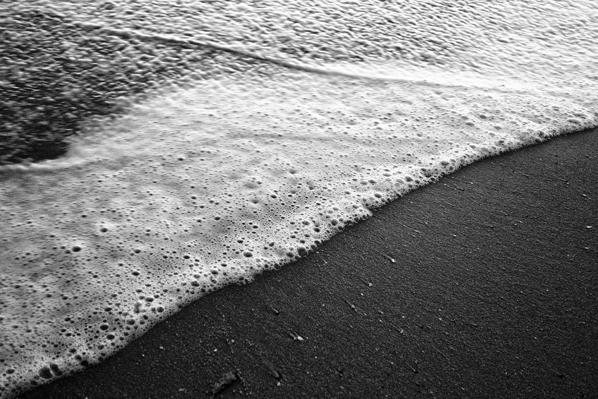 Foam from a wave recedes on the sand of Seacliff State Beach.