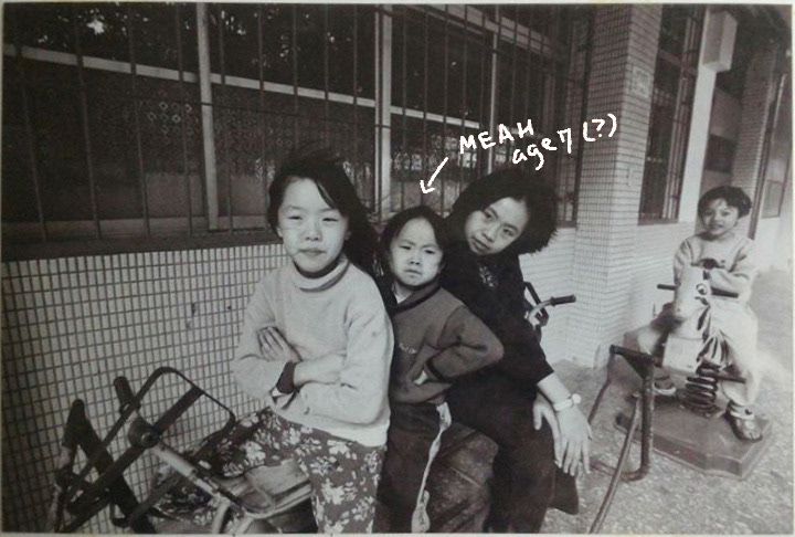 Black and white photo of Meah and other kids. Meah is making an angry face.