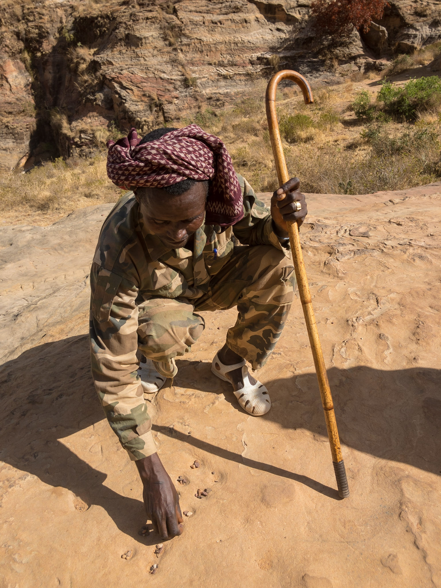 A guide plays the game of bao, hewn out of the rock along the path to Maryam Korkor Church, Tigray, Ethiopia