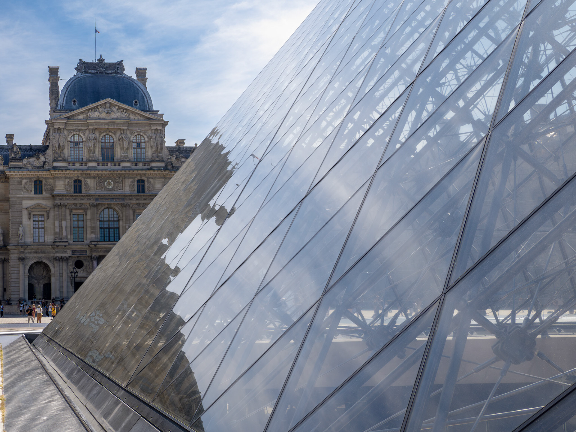 The triangular and diamon-shapes of the glass pyramid of the Louvre museum dominate this view of the museum building