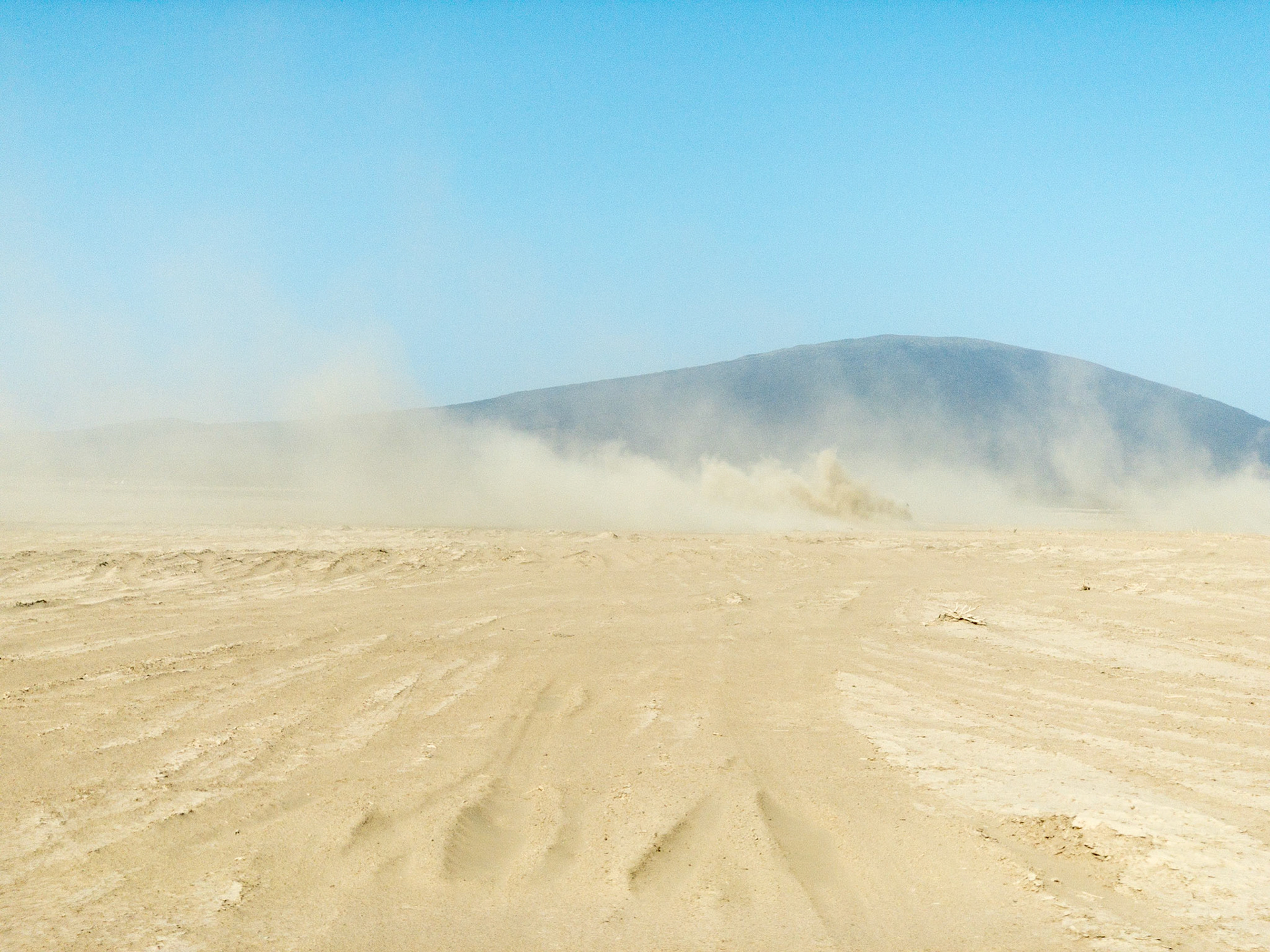 Wind-blown fine sand rises high into a clear blue sky in the Danakil Desert in Etiopia's Danakil Depression, the hottest, driest, most inhospitable place on Earth.