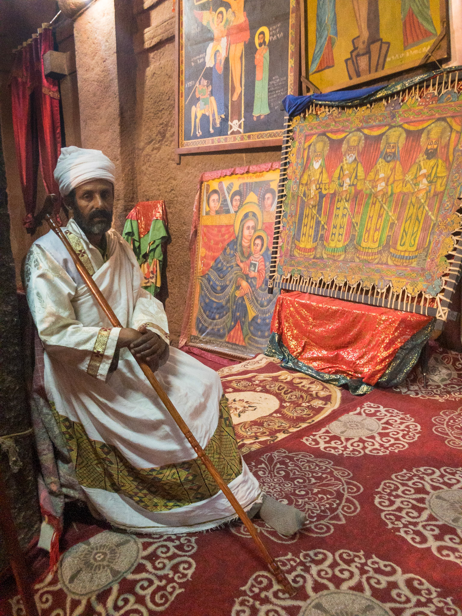 A Priest sits amongst the painted icons of Biete St. Giyorges, lalibela, Ethiopia