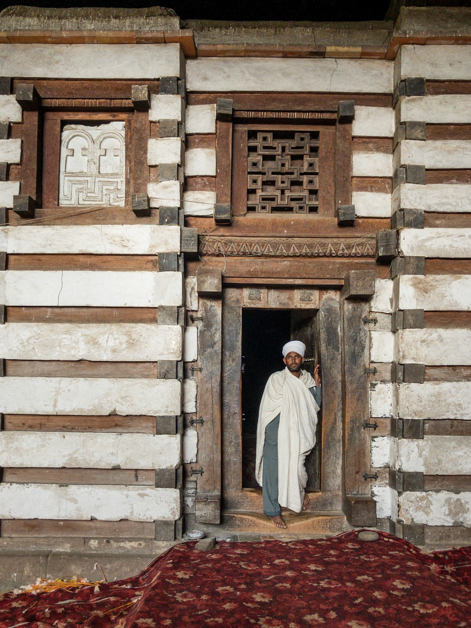 A priest stands in the doorway of the wood and stone Aksumite church of Yemrehana Krestos, near Lalibela, Ethiopia