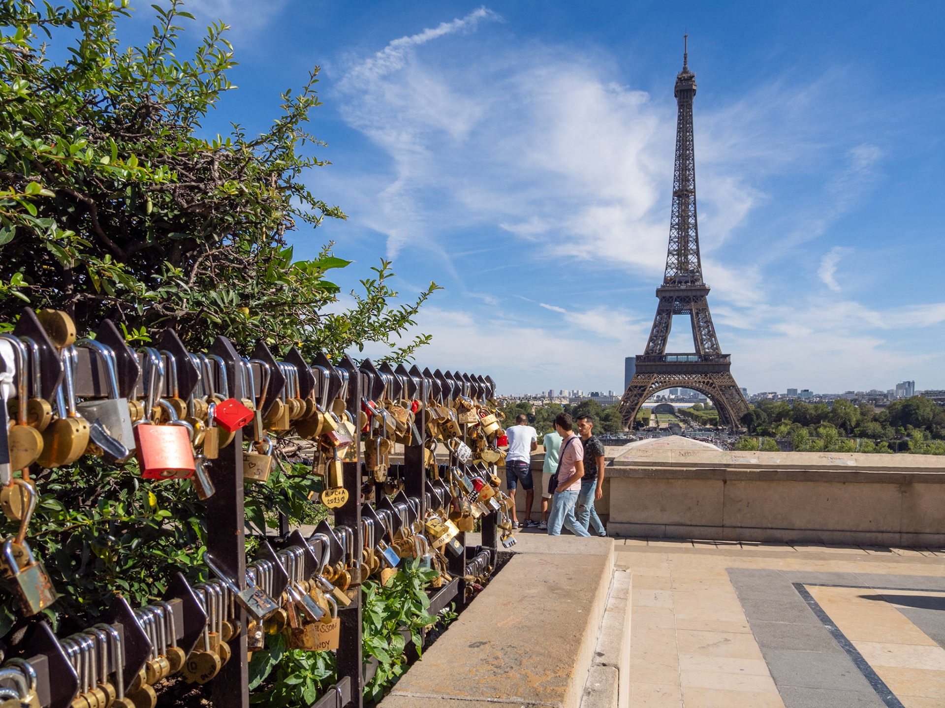 A view from the Trocadero of a series of shiny, metal locks adorn the fencing leading towards the Eiffel Tower.