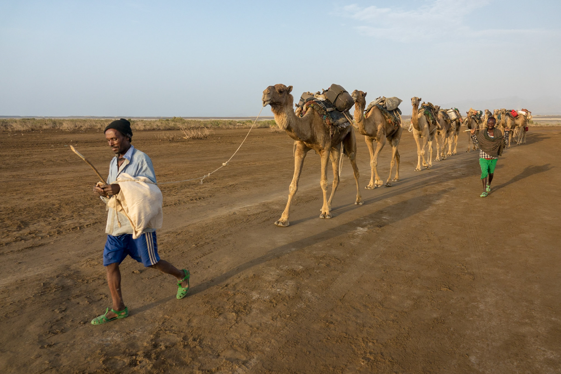 A camel train carrying packs of mined salt is lead by two Afari tribesmen, across the Asale salt pan in Ethiopia’s Danakil Depression, the hottest, driest, most inhospitable place on Earth.
