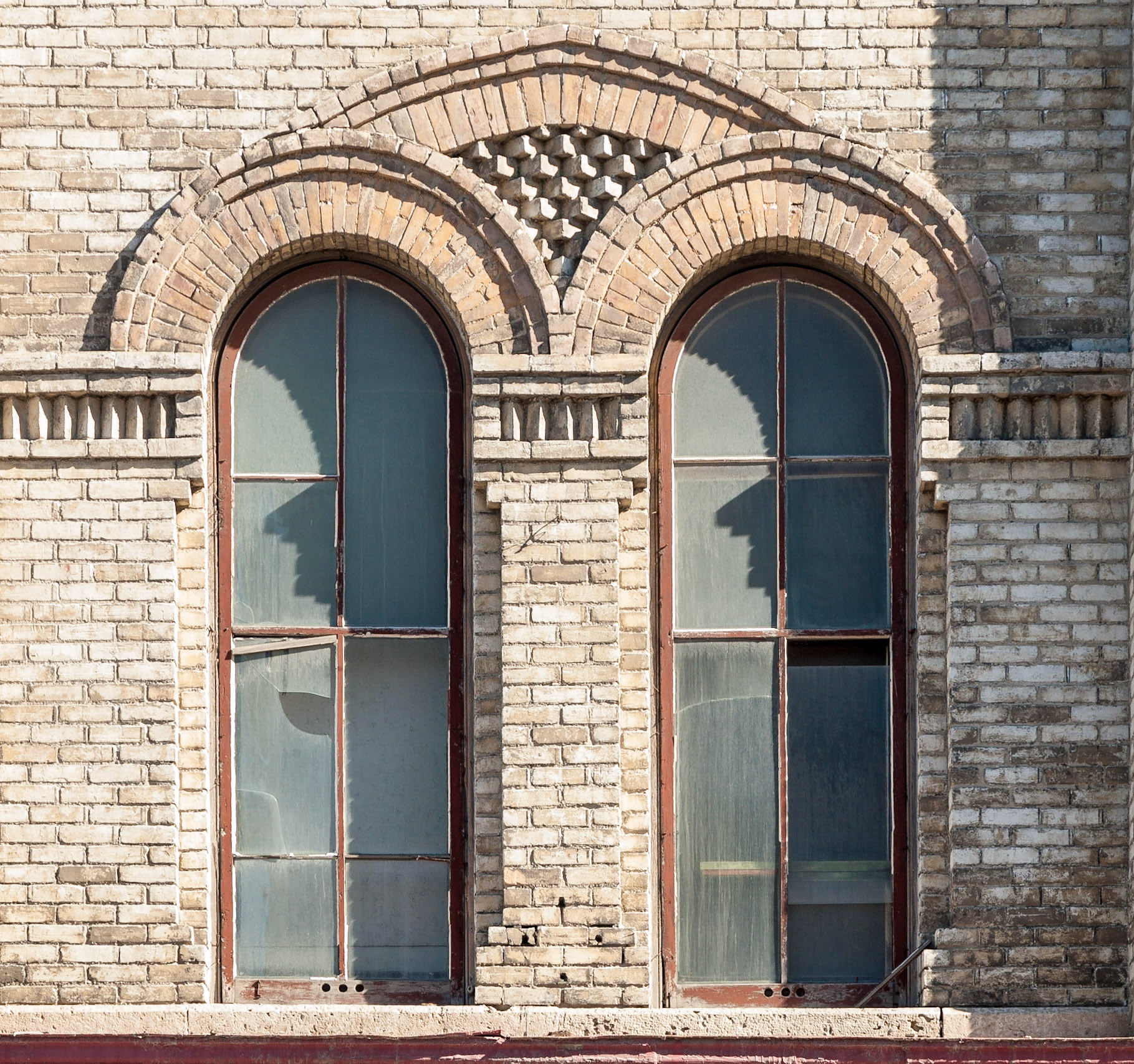 Mottled yellow brick building with ornate brickwork above round-topped  windows in the Exchange District, Winnipeg, Manitoba, Canada