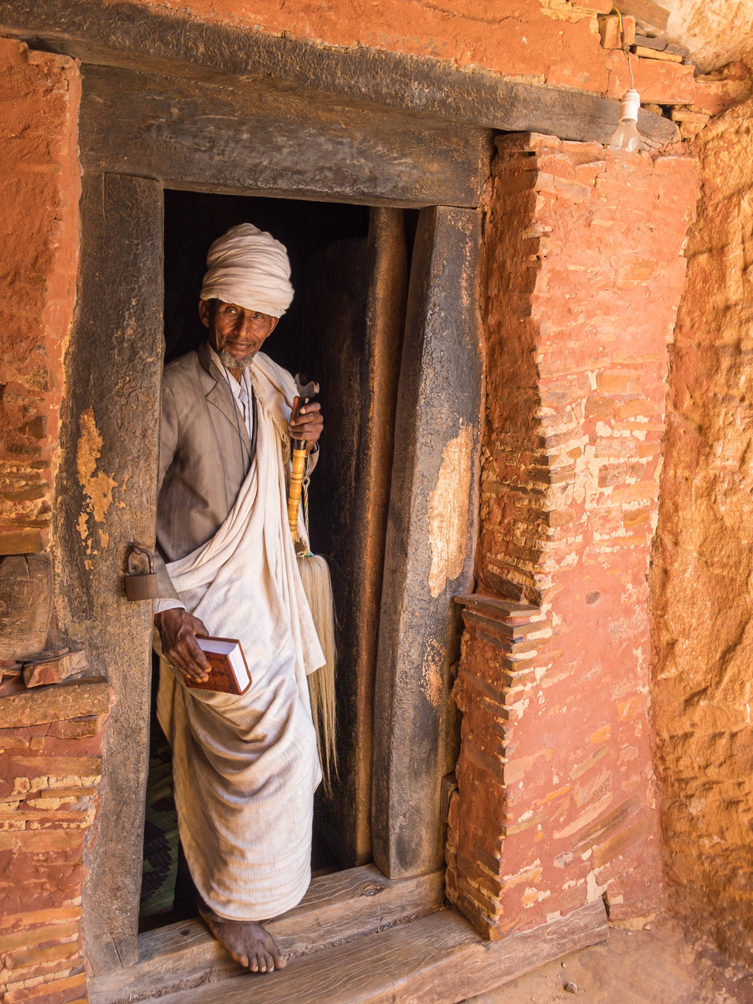 A priest stands in the doorway of Abuan Yemata Guh monlithic rock-hewn church, Tigray, Ethiopia