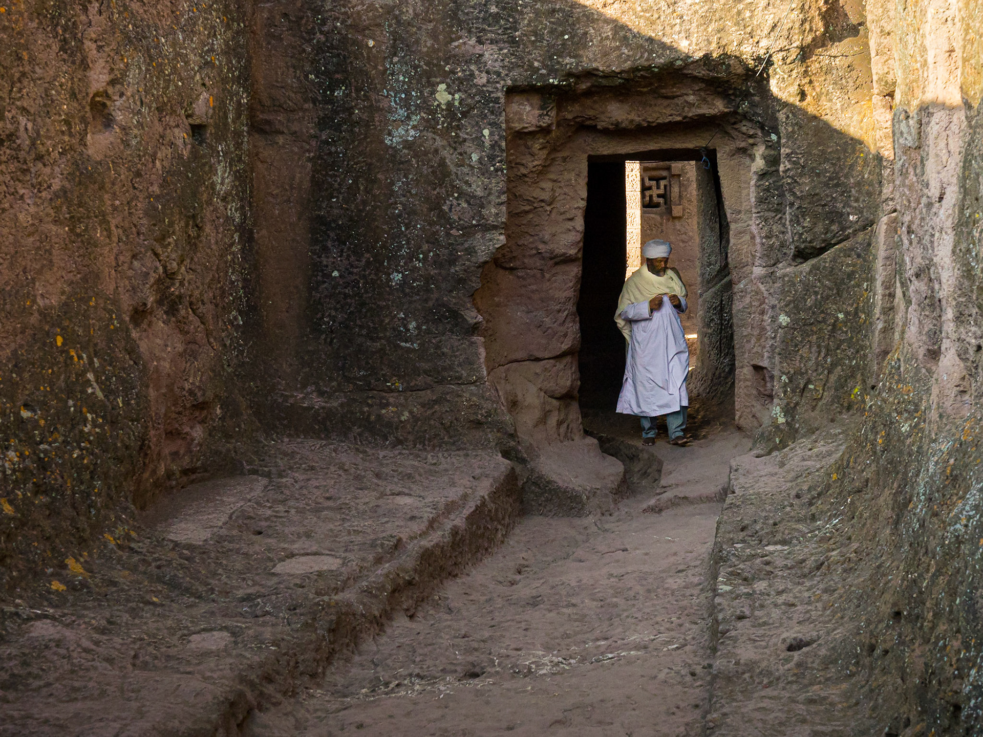 A priest navigates one of the many passages leading between the rock-hewn churches of Lalibela, Ethiopia