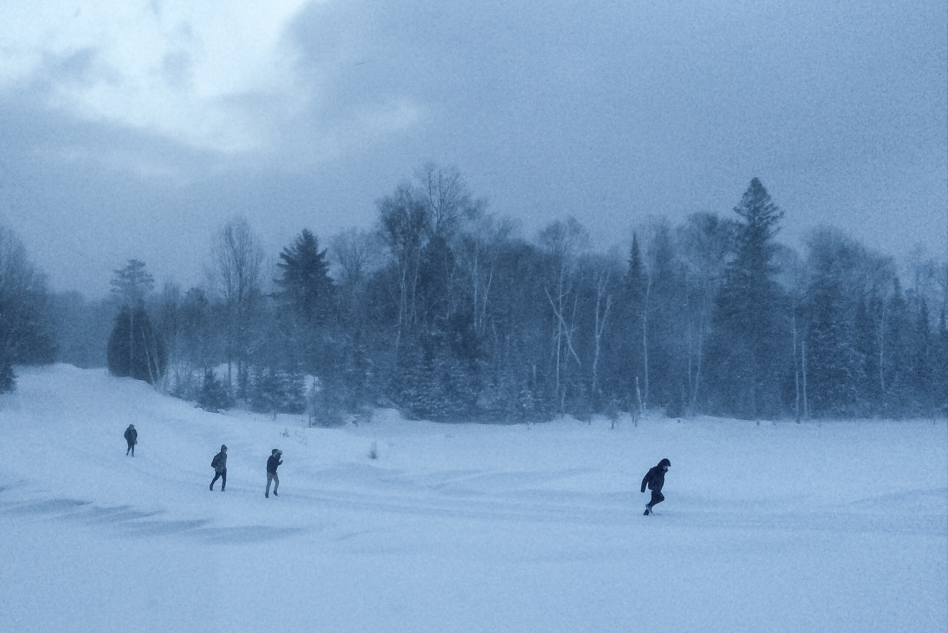 Children run down a rural road on a grey, snowy day on their way to school.