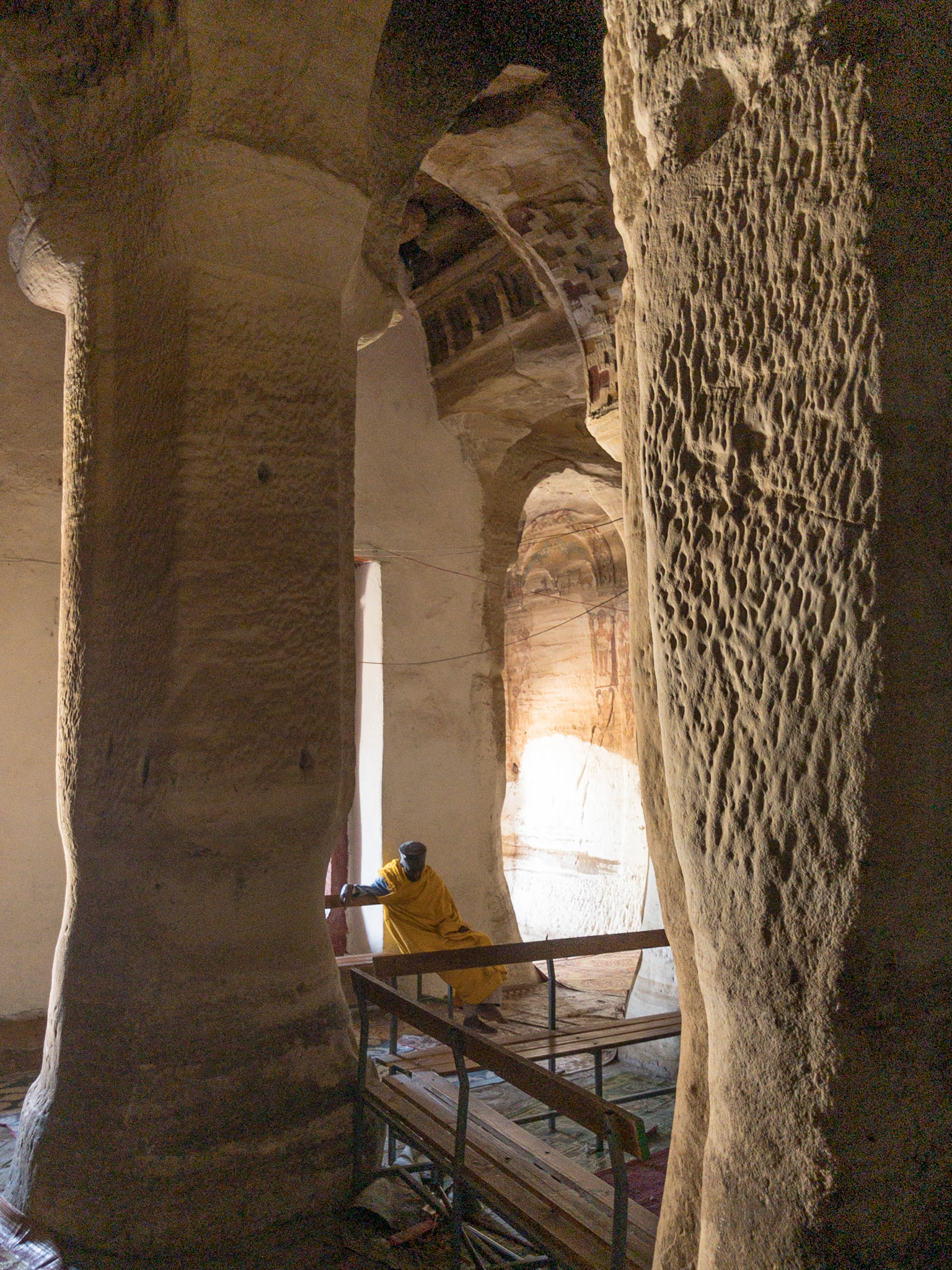 A lone priest sits amongst the rock-hewn pillars of Maryam Korkor Church, Tigray, Ethiopia