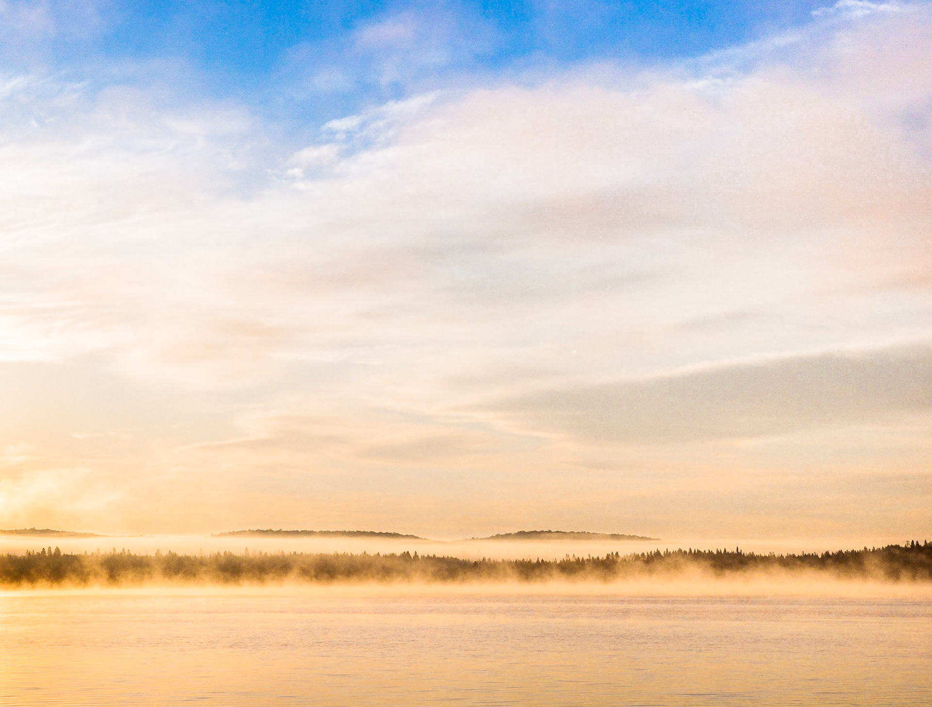 Colourful early morning mist and light clouds over Biggar Lake in Algonquin Provincial Park in northern Ontario