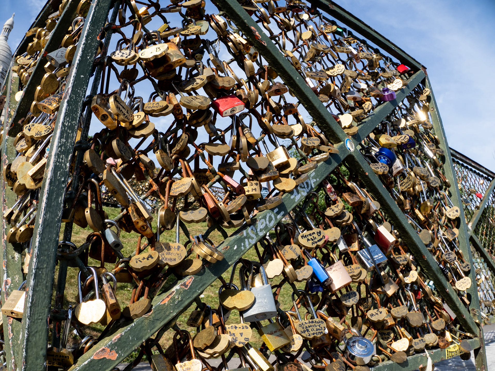 Hundreds of shiny metal locks are attached to the metal grate fencing around Sacré Coeur Basilica on Montmatre, Paris