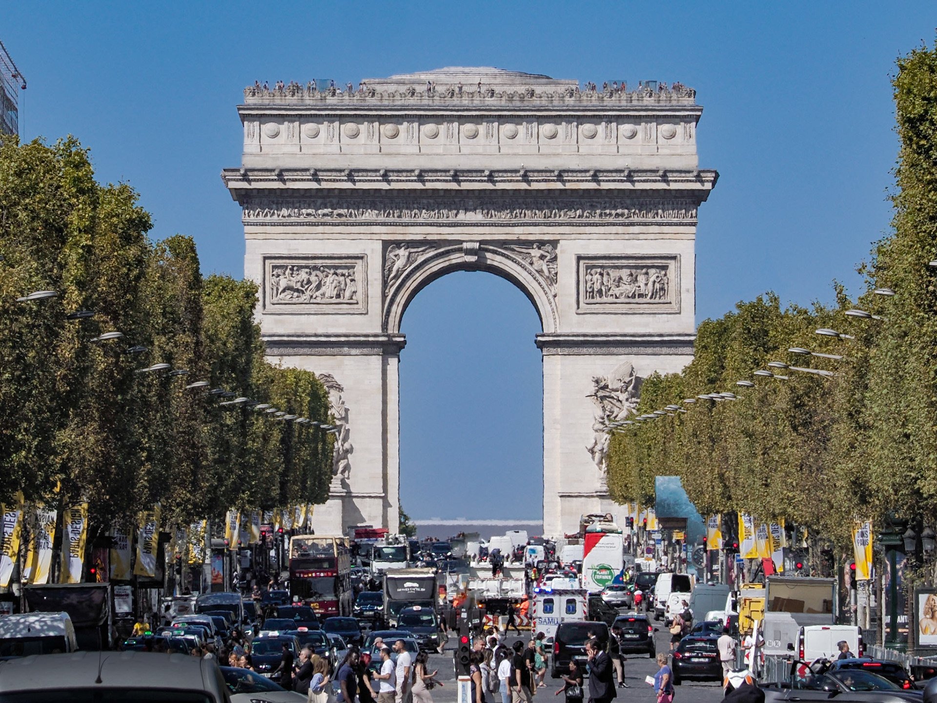 The famous Arc de Triomphe fills most of the view and dominates the tree-lined view and. the crush of traffic up the Champs-Élysées in Paris, France