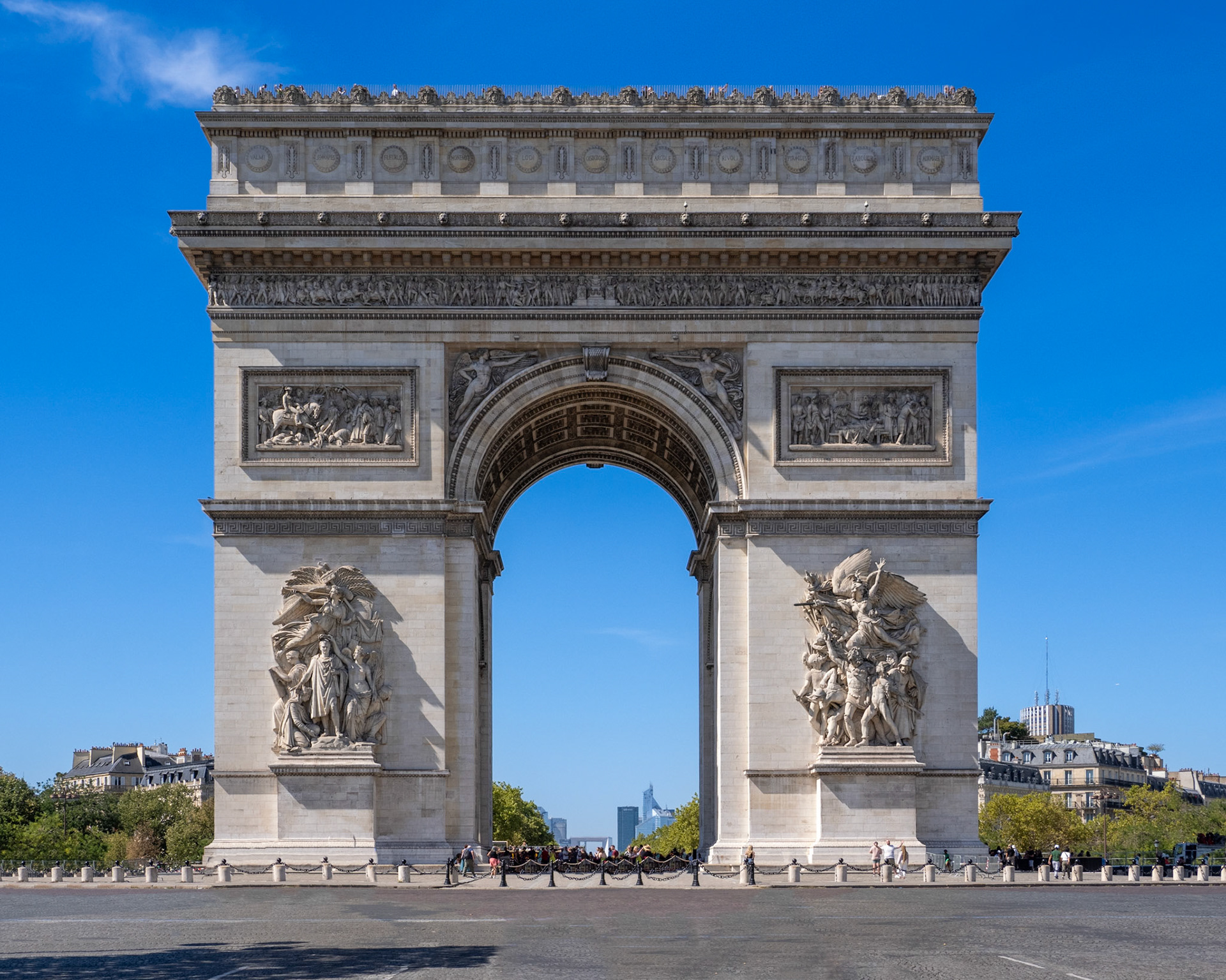 The Arc de Triomphe looms large, filling most of the view with a clear blue sky above and an empty street in front and crowds below.