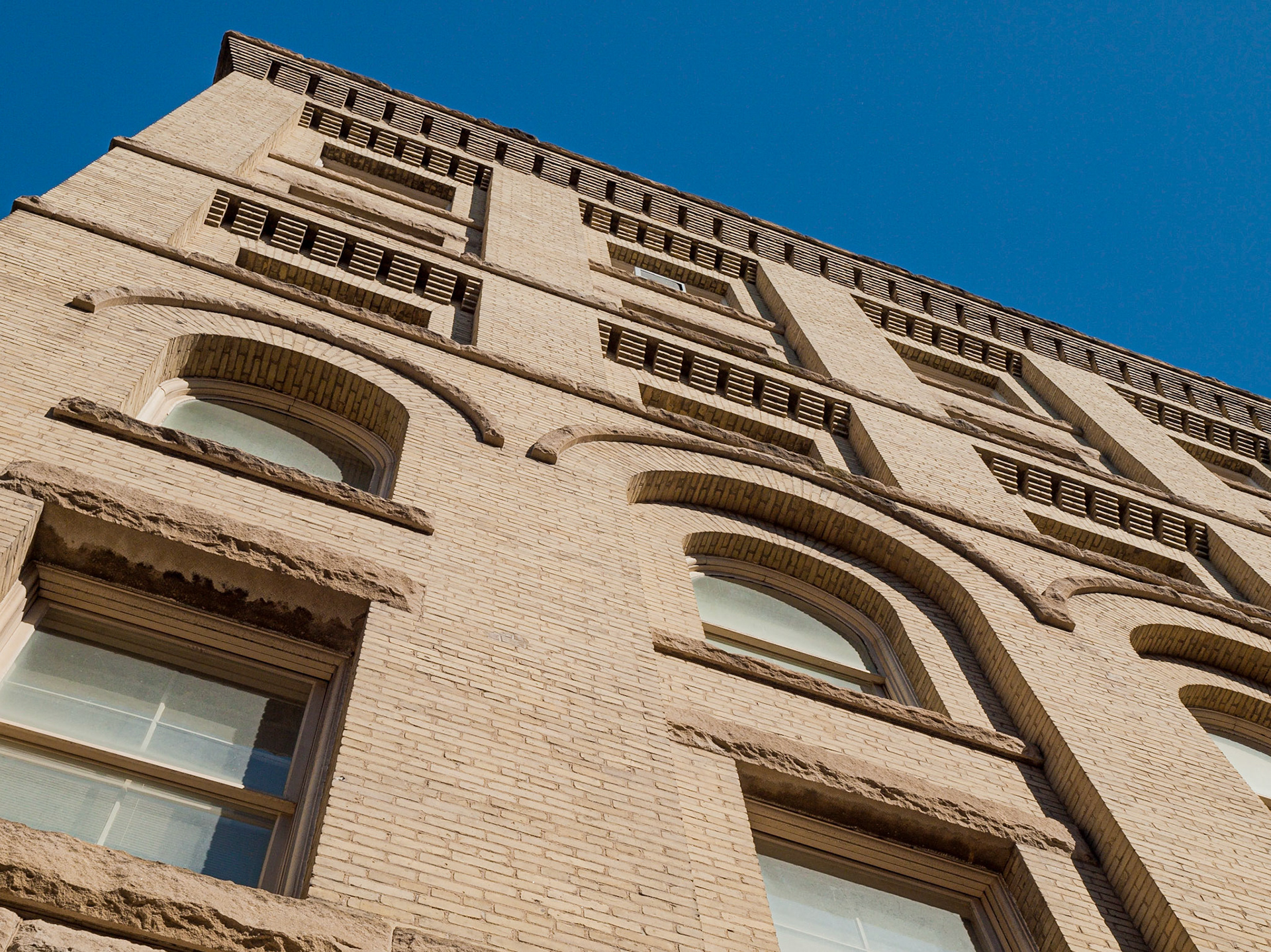 Curved and rectagualr windows of a yellow brick building in The Exchange District, Winnipeg, Manitoba, Canada
