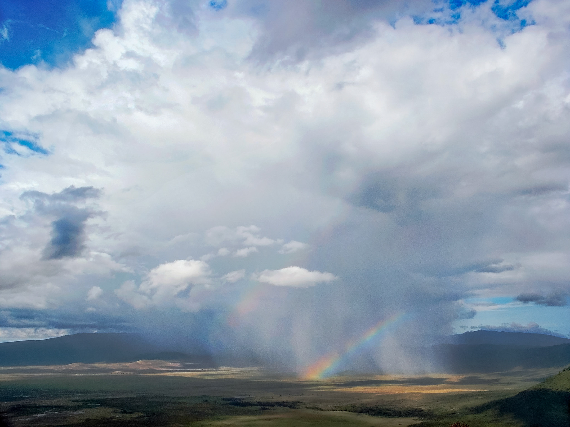 The storm, complete with rain and a rainbow, makes it way across the great bowl of the Ngorongoro Crater.