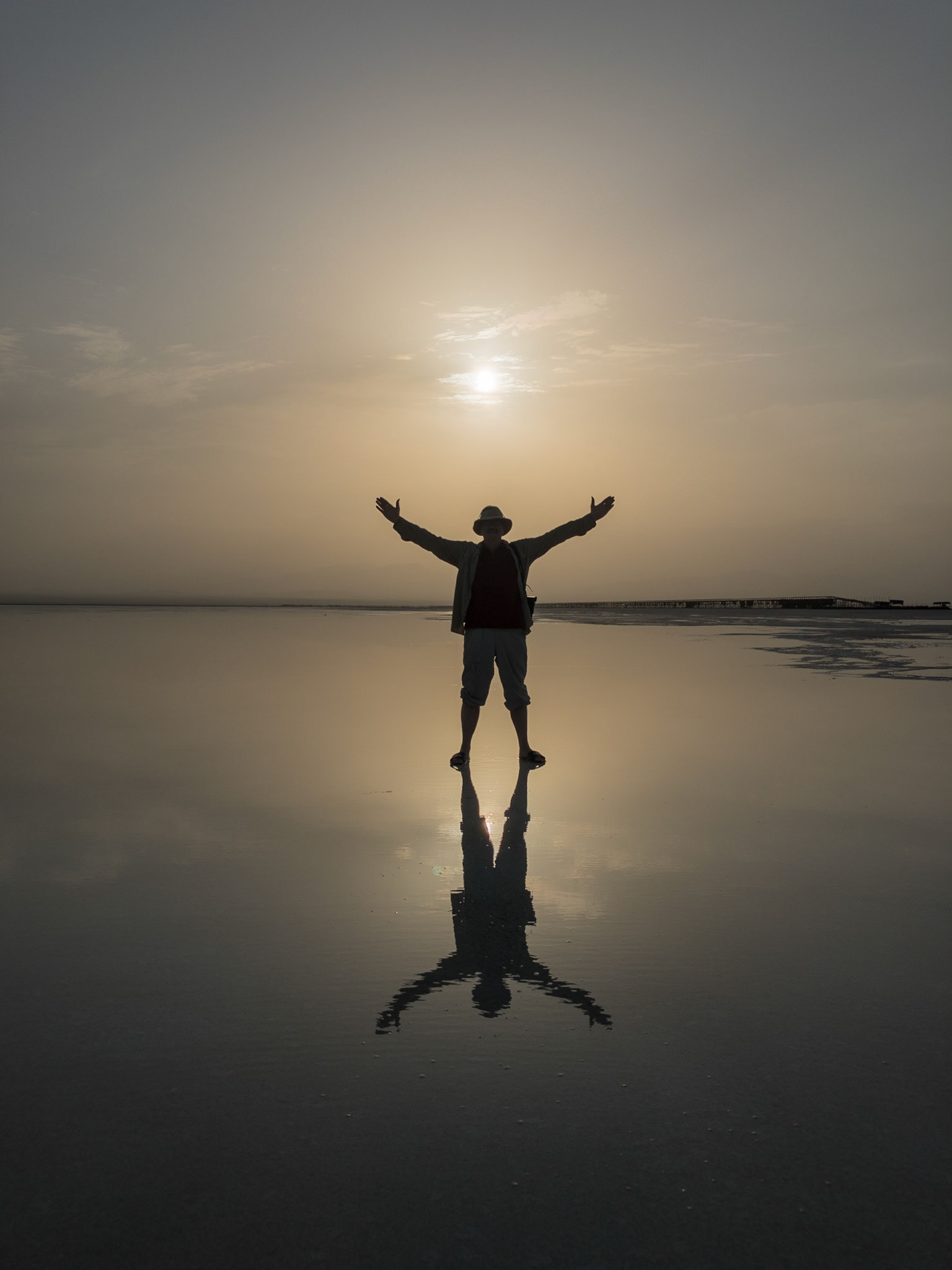 The mirrored image of a tourist, with arms spread wide, is silhouetted against the warmth of sunset over Lake Asale in Ethiopia's hot, dry Danakil Depression, the most inhospitable place on Earth.