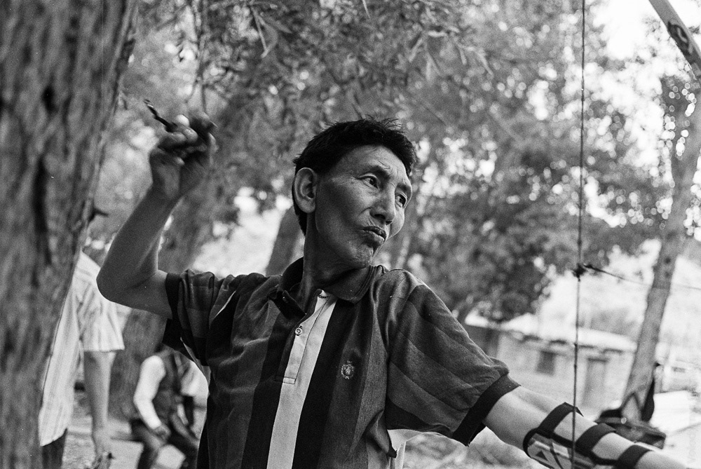 A man is practicing archery. He appears relatively wealthy by local standards.