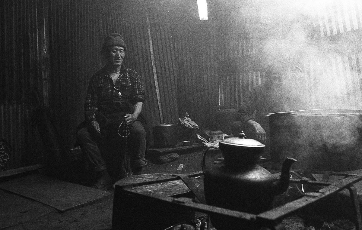 The village bar that serves raksi appears to be a shed made of roofing iron, with a bonfire blazing inside.