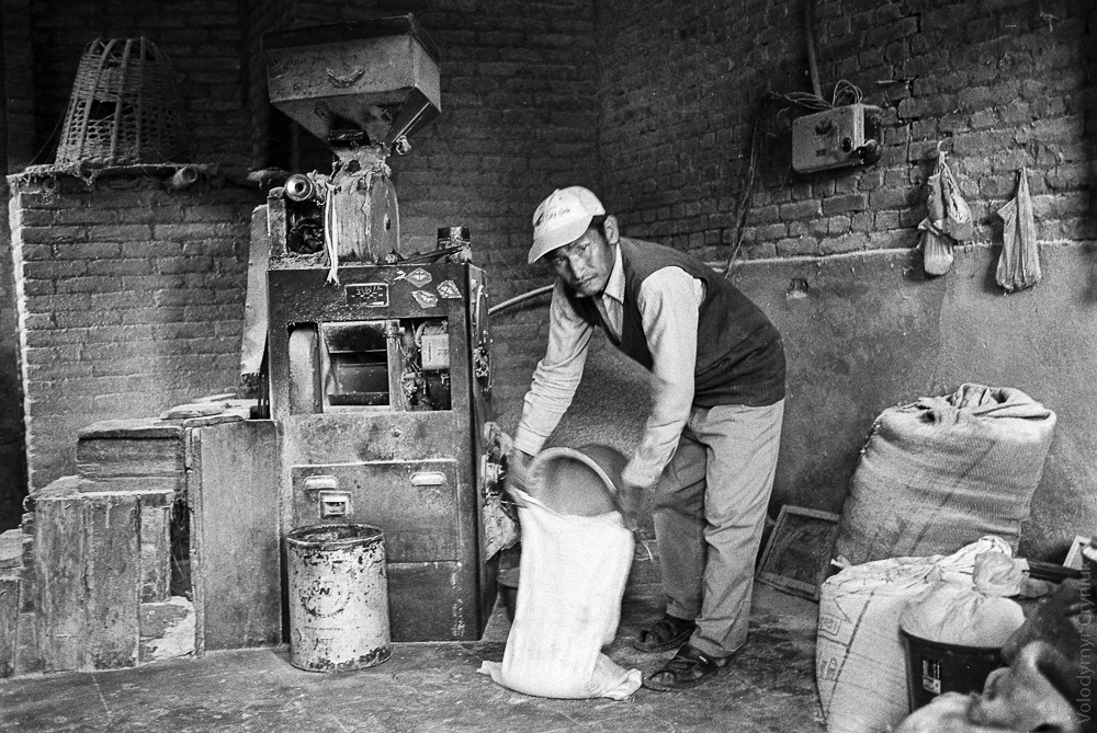 A flour mill worker stands at his post, laboring at his job, perhaps for his entire life. Same to previous photo, met him again there after several years at the same place.