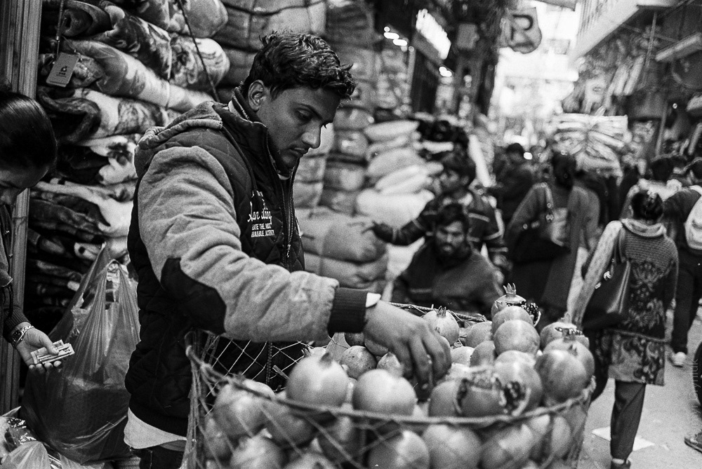 Pomegranate vendor navigates his way through the crowd, pushing a bike loaded with fresh, pomegranates.