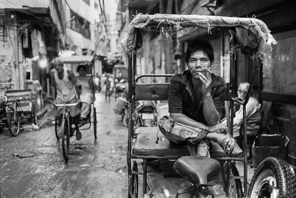 A bicycle rickshaw driver takes a break and enjoys a bidi cigarette.