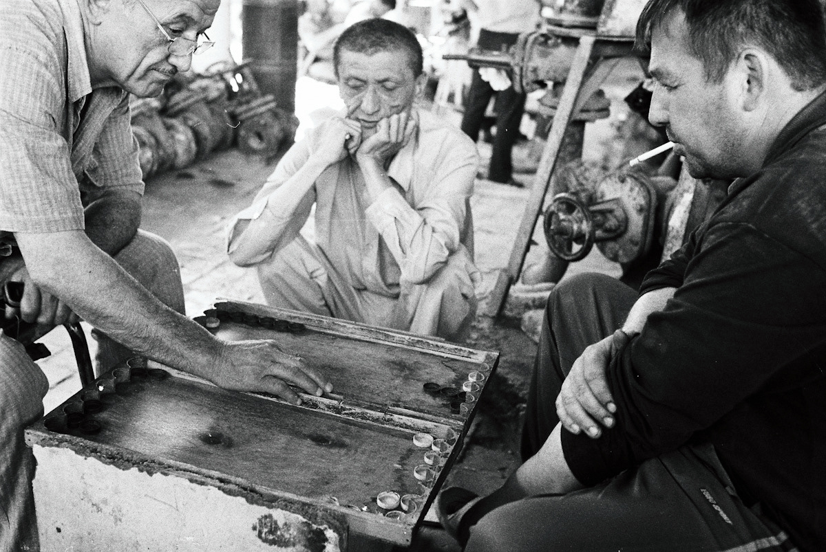 Vendors take a moment to unwind and enjoy a game of backgammon. Osh hardware market in Kyrgyzstan.