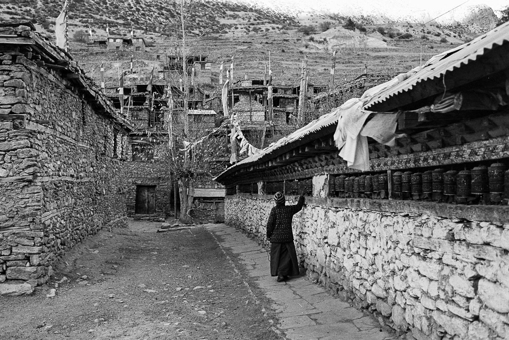 A wall of Buddhist prayer drums, each inscribed with sacred mantras, creates a symphony of spiritual energy as visitors spin them to send their prayers and wishes to the heavens.