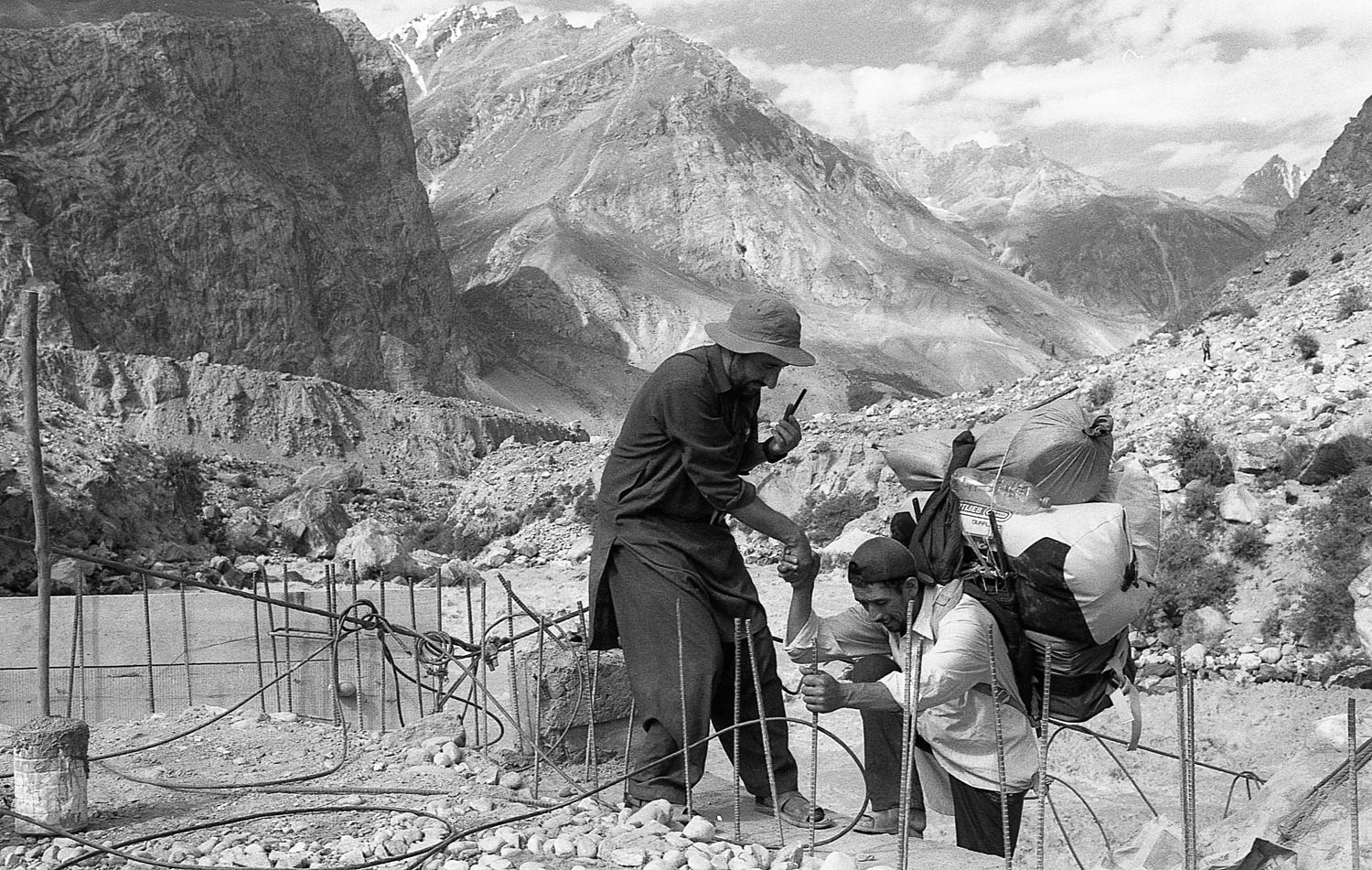 With the previous bridge swept away by the relentless Braldu river,  porter crosses a temporary bridge.