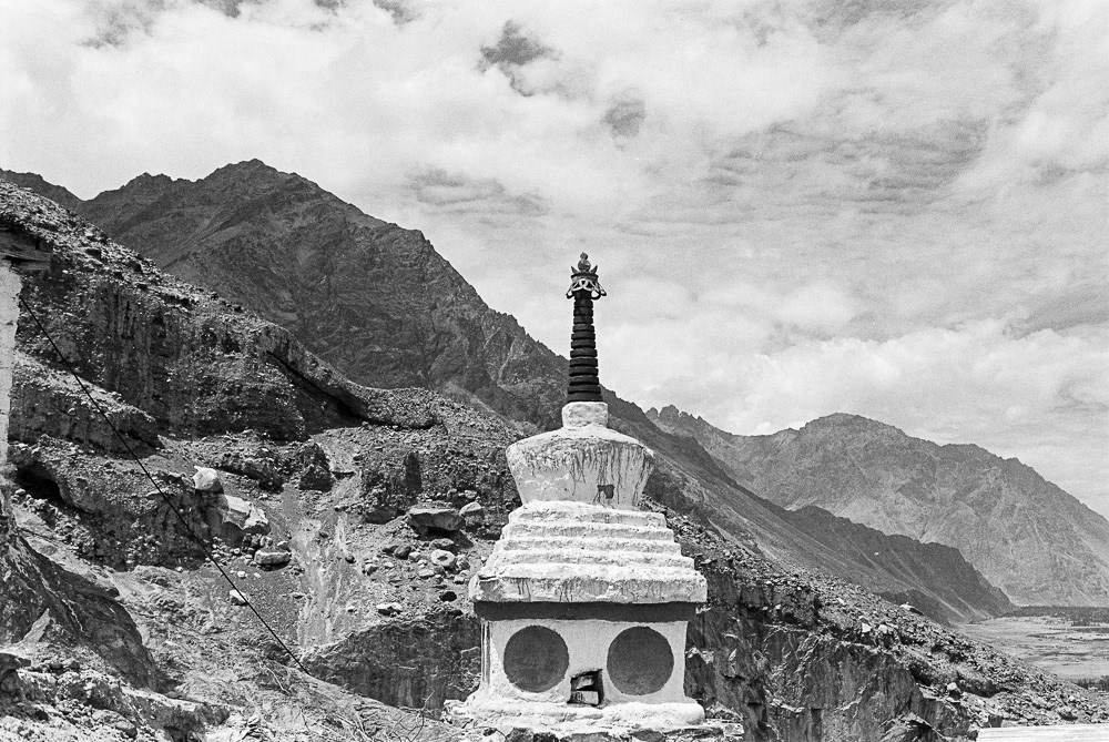 A magnificent Buddhist chorten stands in serene isolation, framed against the backdrop of the rugged peaks of the Ladakh mountain range.