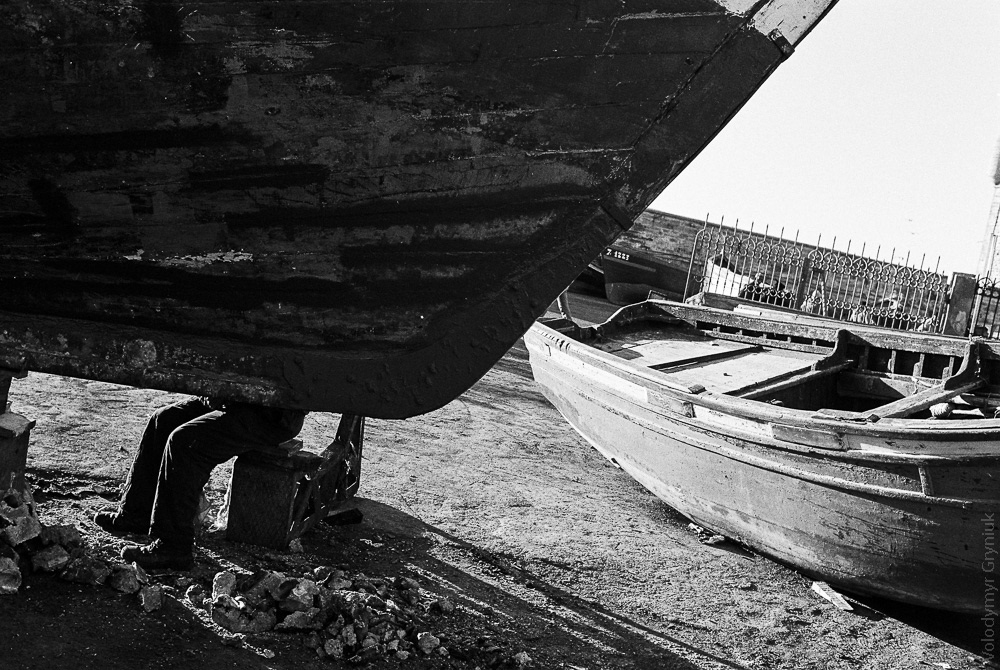 Repairing a fisherman's boat in Essaouira's harbor.