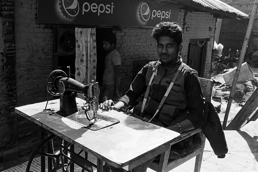 Craftsmanship in the streets: A tailor works away at his machine, providing locals and tourists with affordable replicas of famous brands.