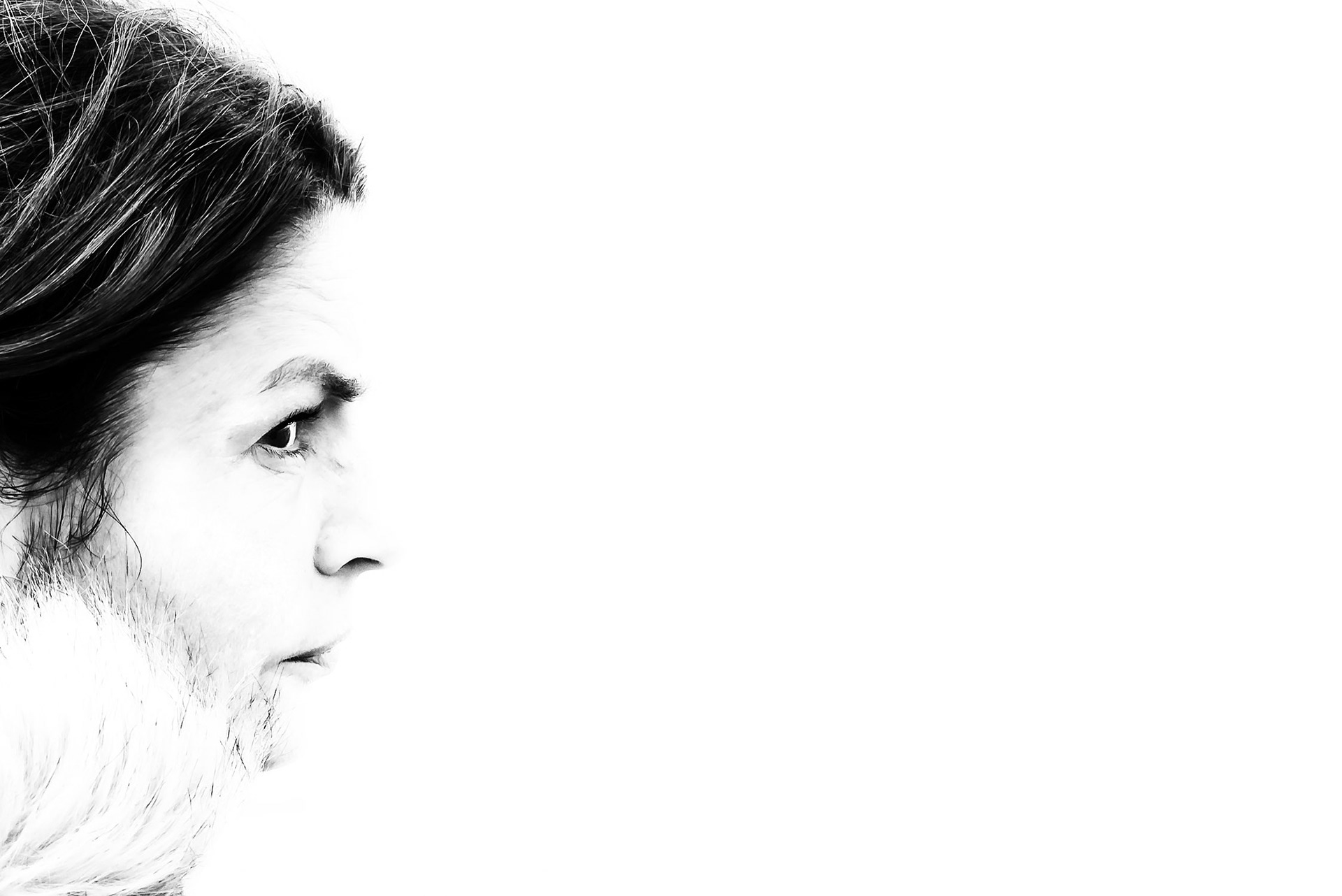 A black and white profile image of a woman's face positioned at the extreme left of the image, with the rest of the image being negative white space