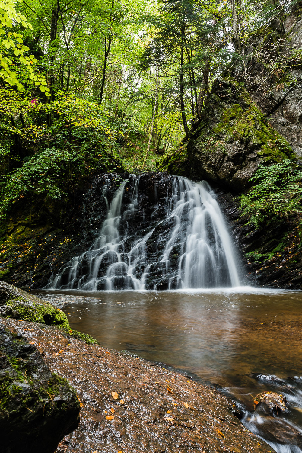 A long exposure of the lower waterfall in Fairy Glen, Rosemarkie, Black Isle, Scottish Highlands, surrounded by green summer foliage