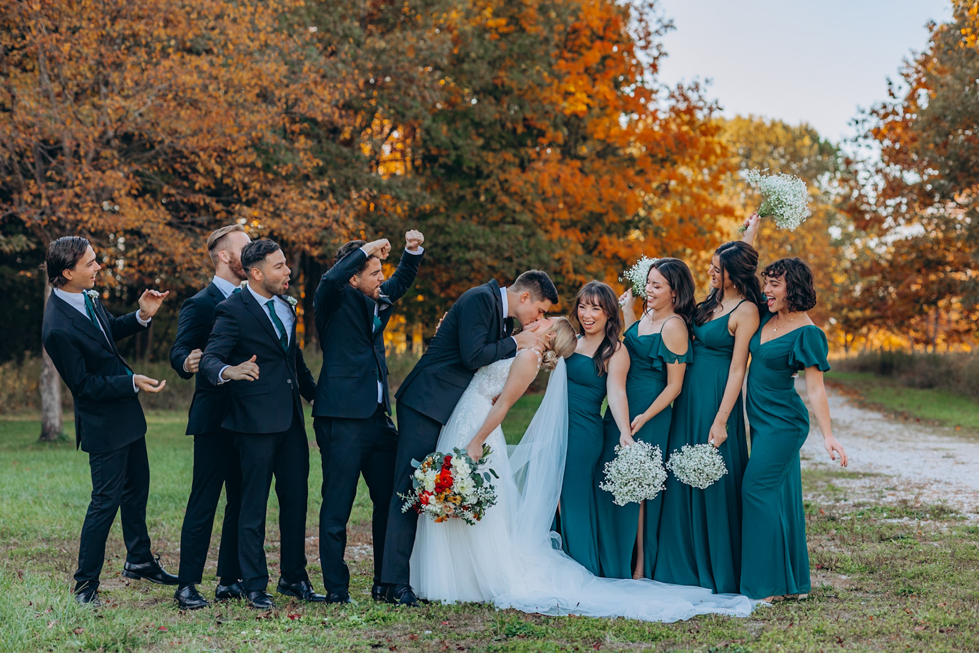 bride and groom share a kiss as the bridal party celebrates