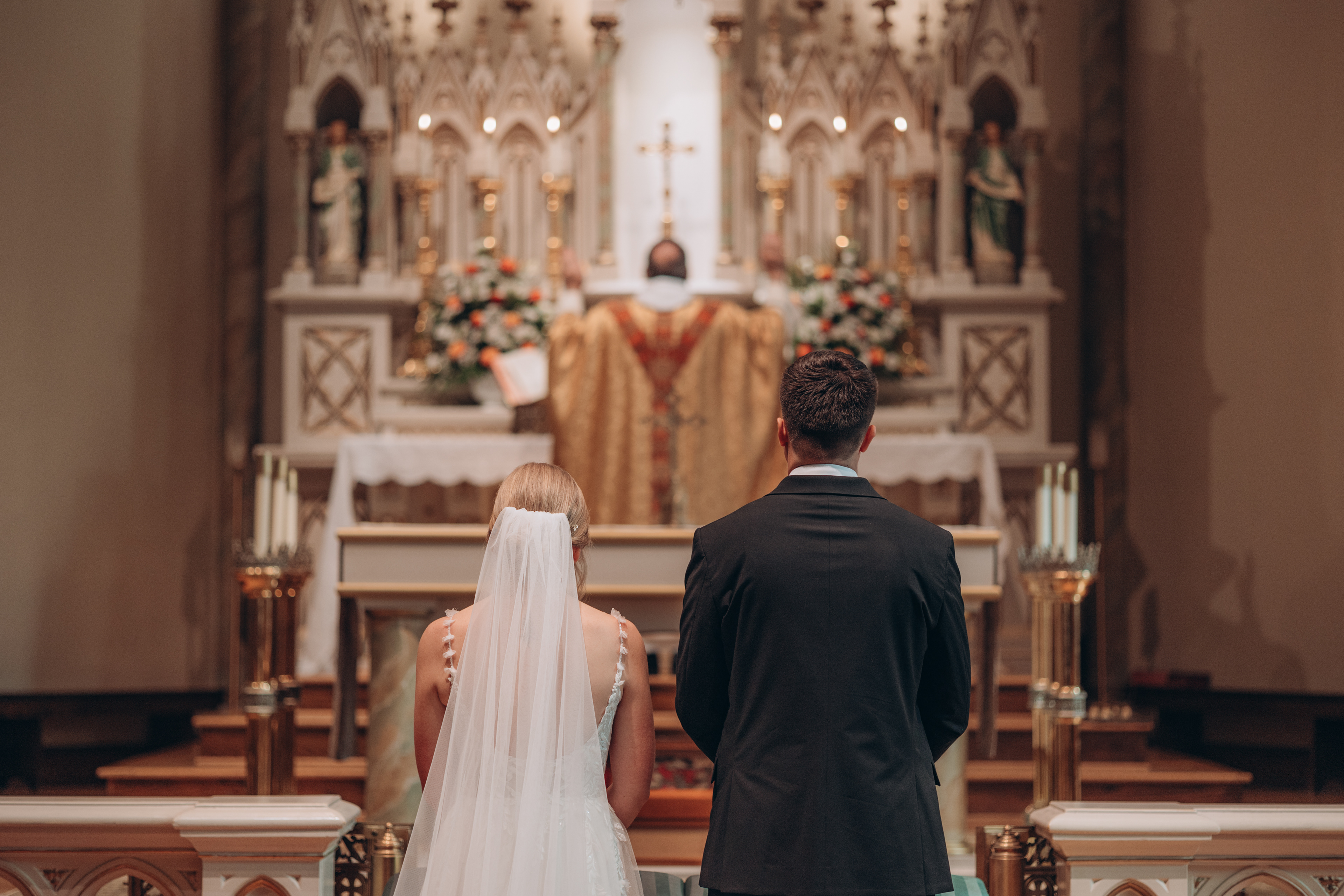A bride and groom kneeling before the Lord in their nuptial mass