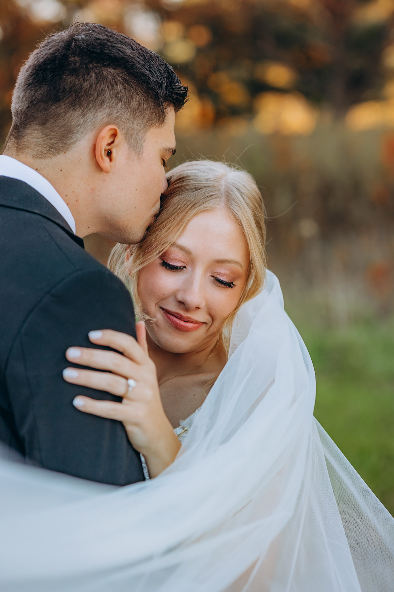 groom gently kisses his bride's temple