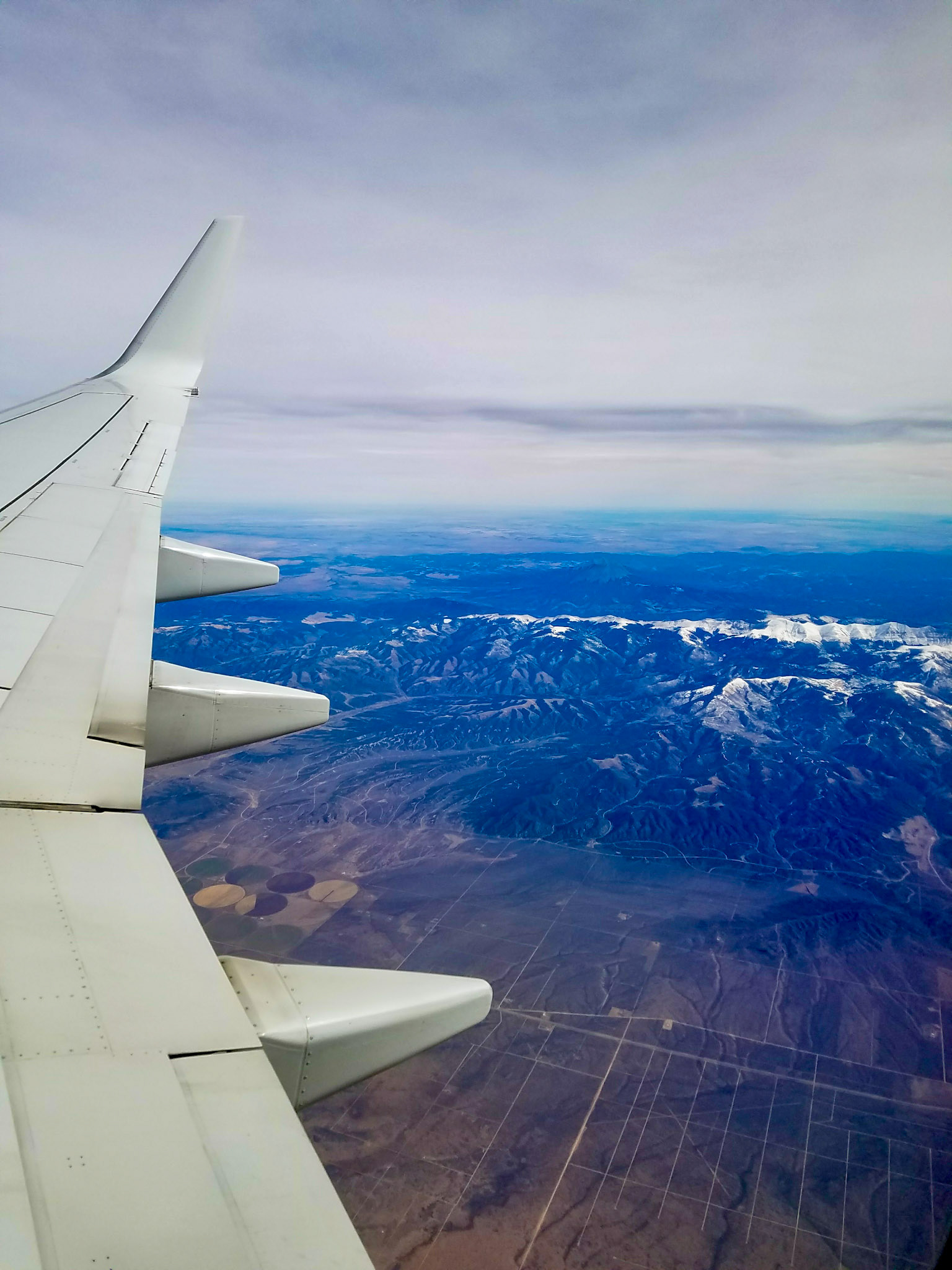 Colorado, US - Nov 1, 2017: Fields and snow-capped mountains beneath airplane wing