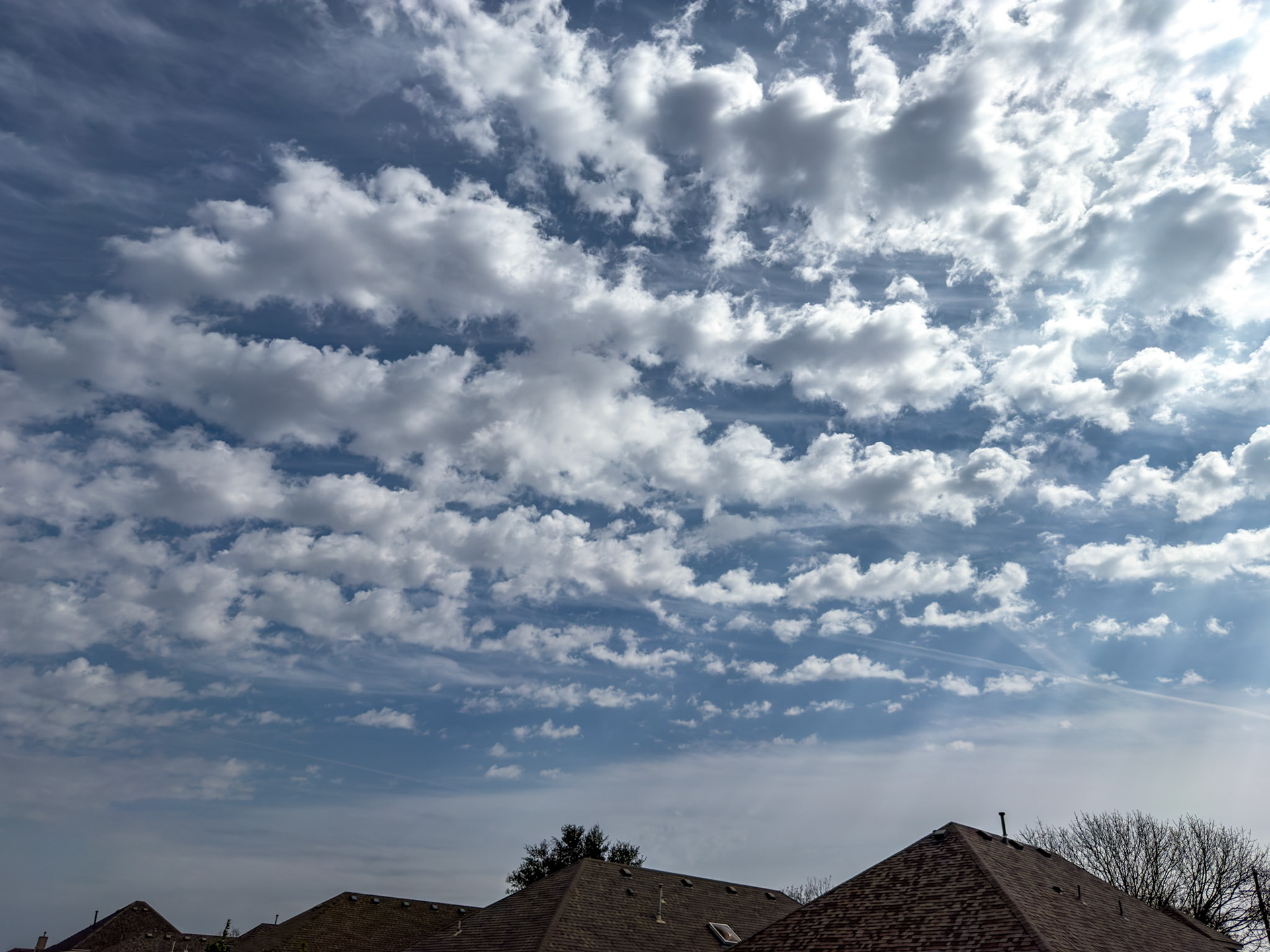 McKinney, TX, US - Feb 21, 2026: Puffy cumulus clouds over suburban rooftops