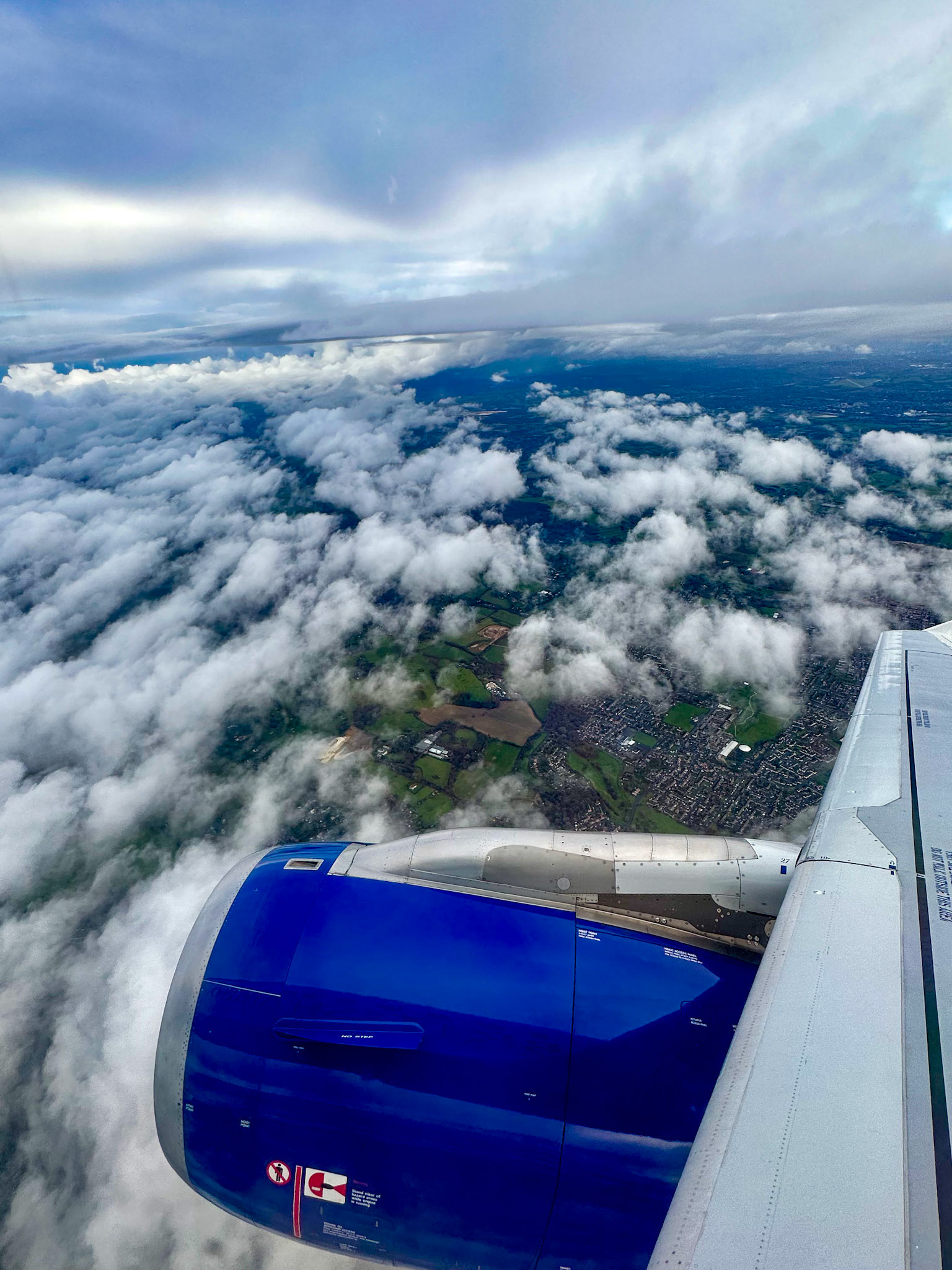 Hillingdon, London, UK - Dec 25, 2022: Airplane wing and puffy clouds over London suburbs