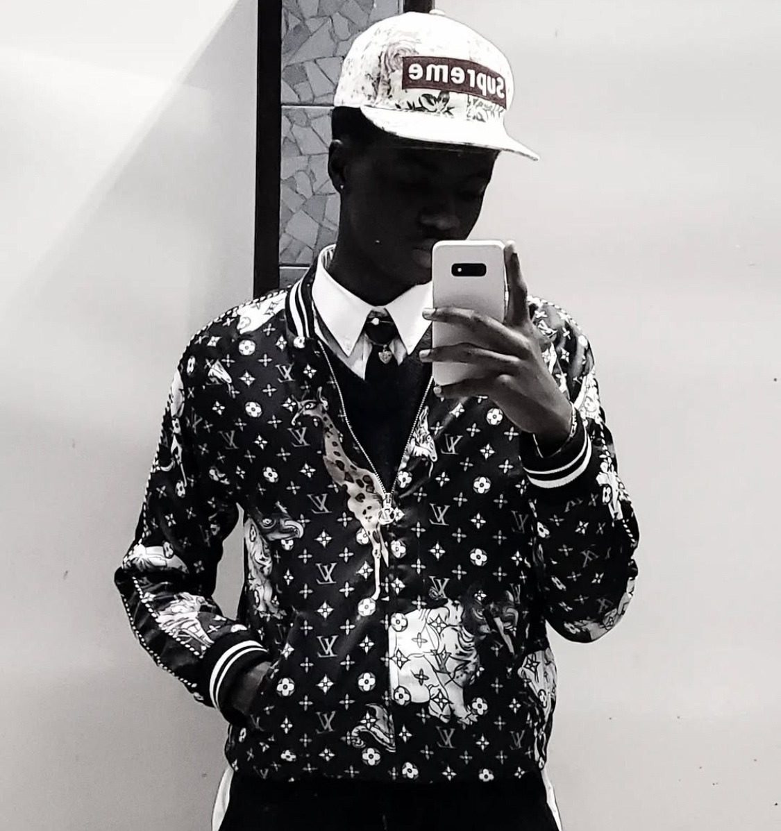 Black and white mirror selfie of Futherlesssun wearing a Supreme cap and Louis Vuitton monogram jacket, reflecting underground fashion and protest culture.