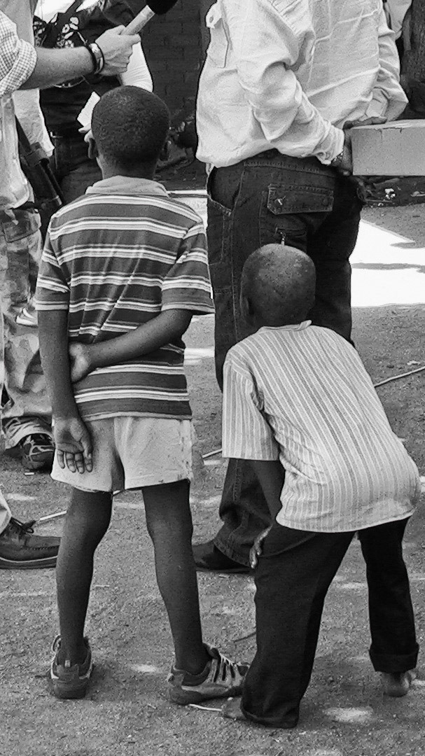 Two young Zimbabwean refugee boys watch a jouralist conduct a TV interview at a refugee transit camp in northern South Africa.