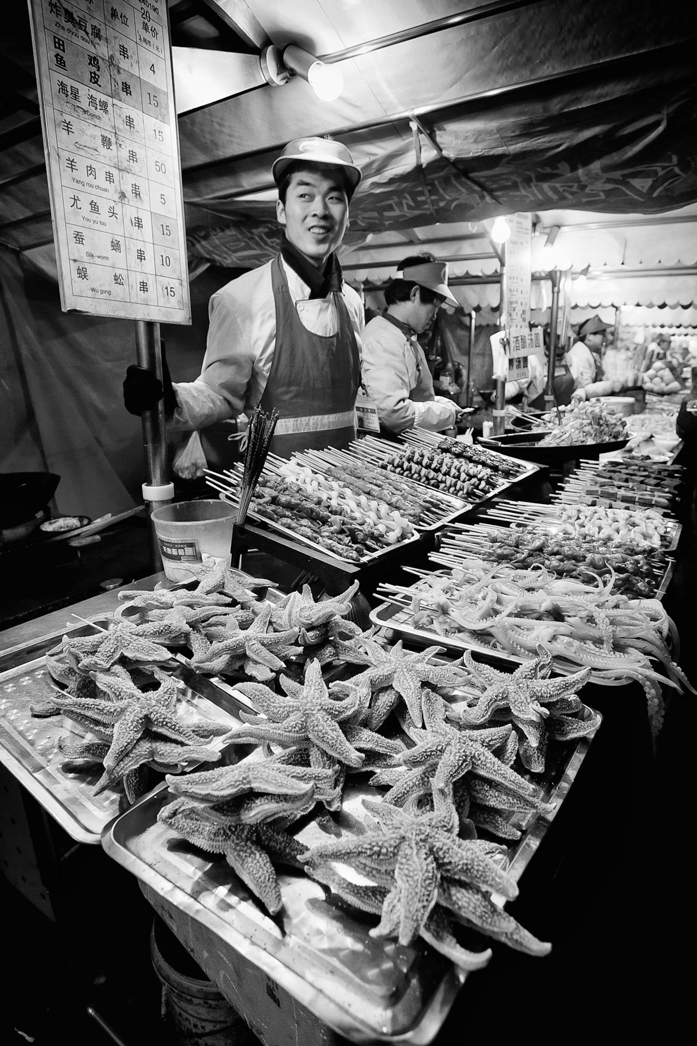 Night time shot of a Beijing street food vendor selling a range of local delicacies including starfish, snake, silk worm and conch.