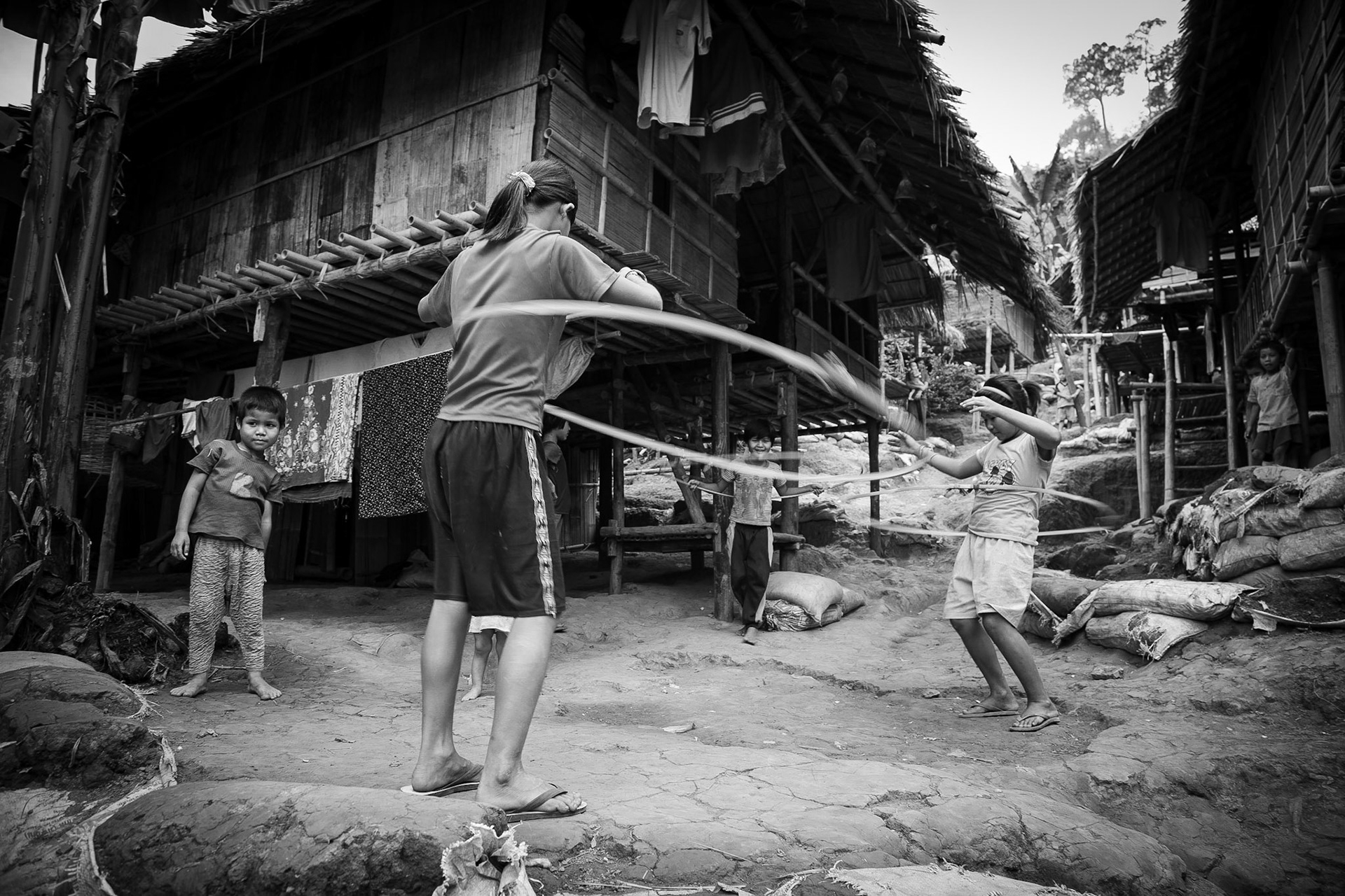 Burmese karen refugee children playing with hula-hoops between the shelters at Tham Hin camp on the Thai, Burma border.