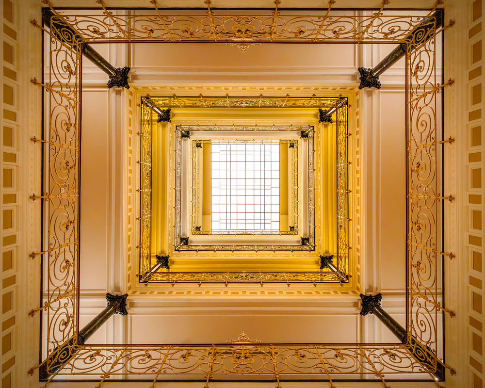 Nicole Holz - Fine Art Editions |  Laeiszhof Hamburg | Architektonische Fotokunst des expressionistischen Treppenhauses. Minimalistisches Fine-Art-Foto einer historischen Klinker-Fassade im Stil des Expressionismus. Eine kontrastreiche, grafische Komposition aus geometrisch angeordneten Fenstern, Emporen und Galerien mit radikaler Symmetrie aus der Serie KONTOR HOUSES von Nicole Holz. Architectural fine art photography of an expressionist staircase. The composition captures the sweeping, monumental lines and sacred gravity of historic corporate architecture through a precise interplay of light and shadow.