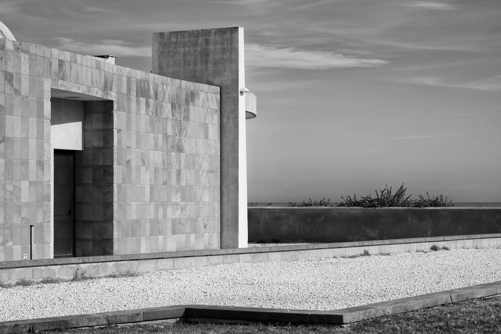 Building, gravel, sky and a glimpse of sea, Ortigia