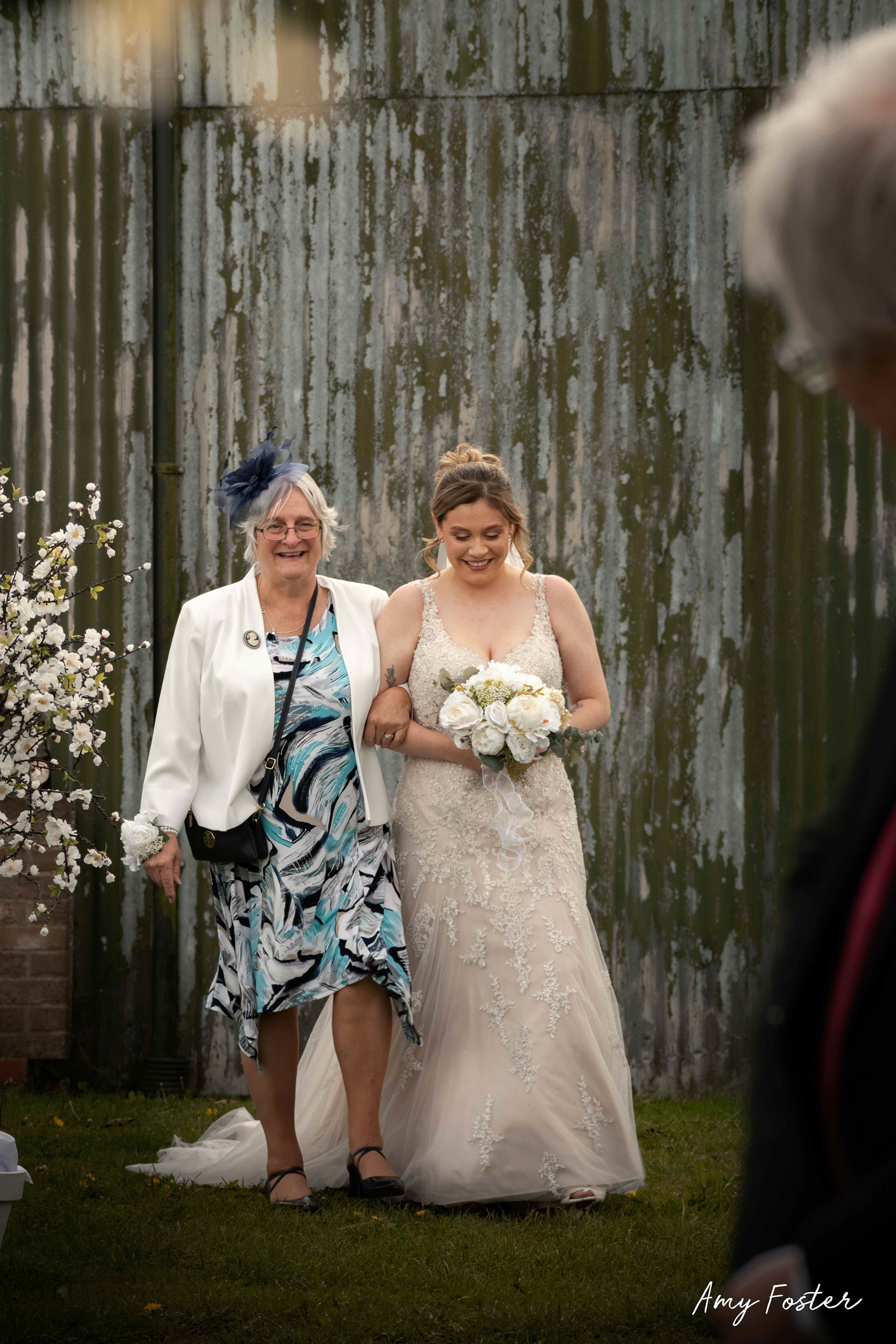 bride walking down the isle smiling with her grandma in outdoor rustic wedding