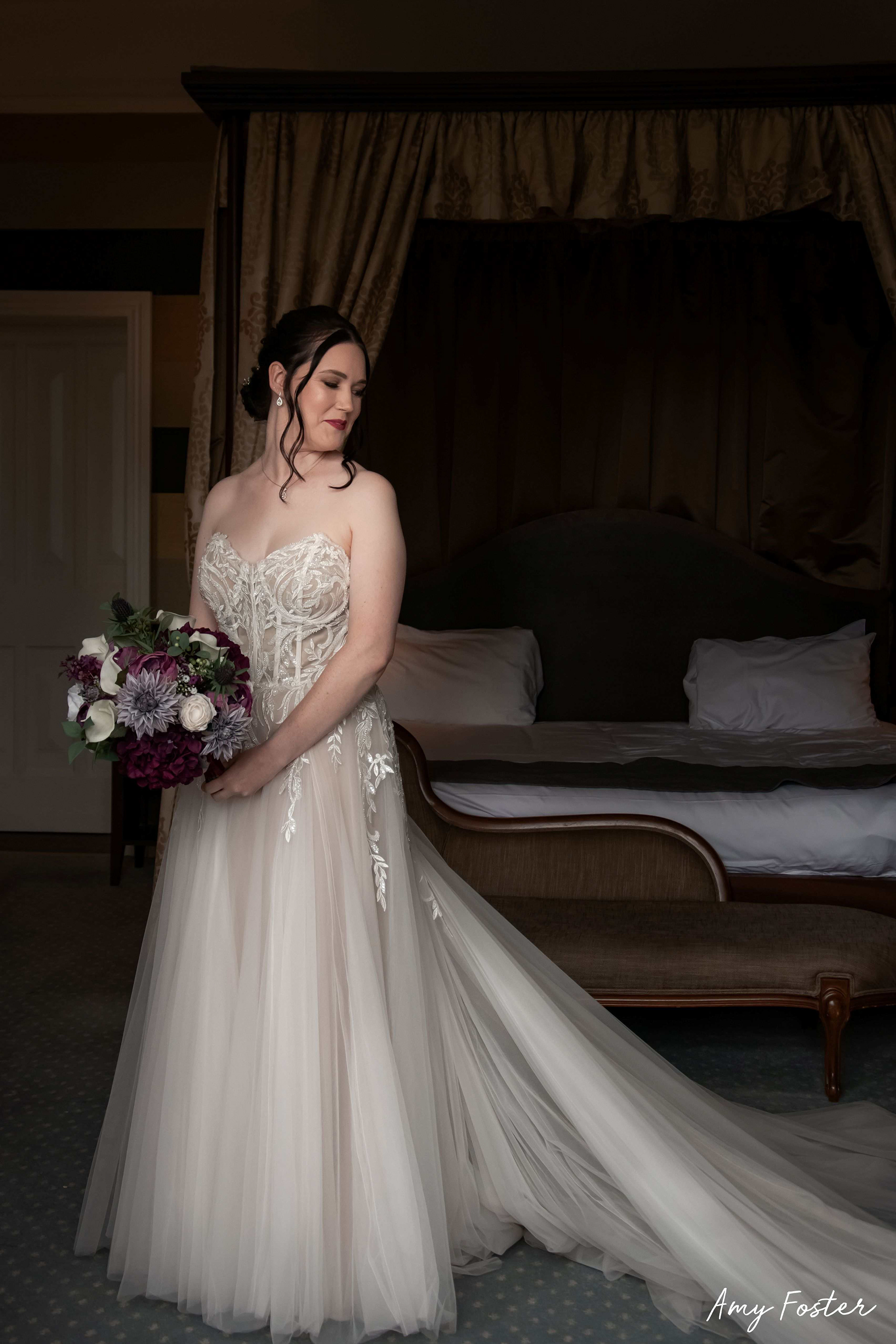 Bride holding purple bouquet in wedding dress during bridal prep 